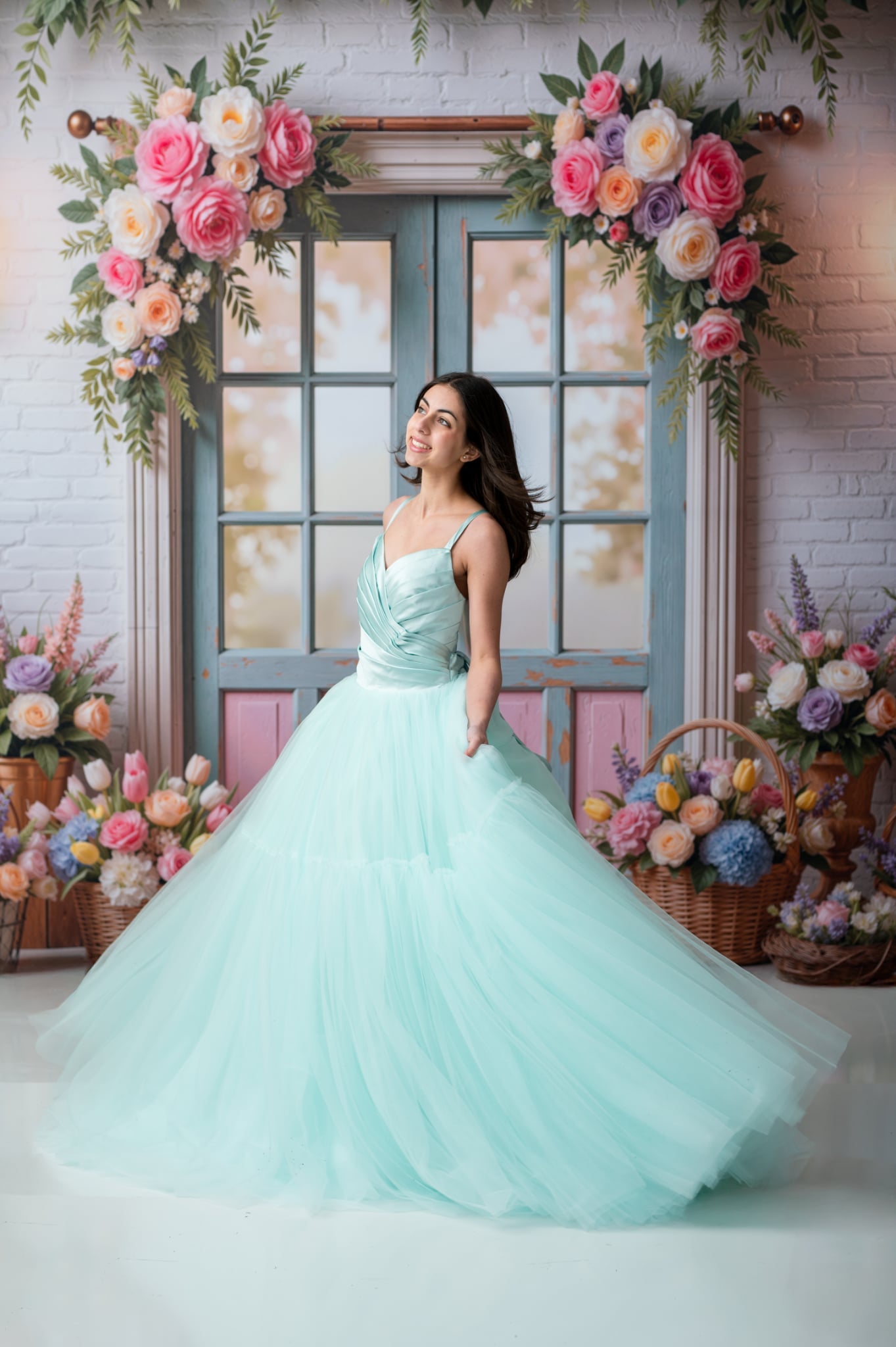 Woman in a light blue dress standing in front of a decorative floral backdrop.