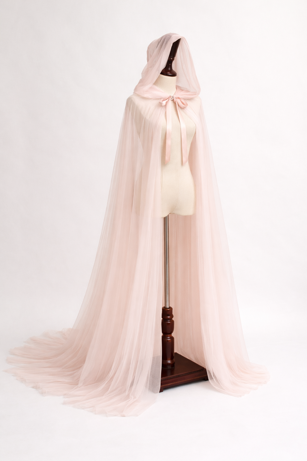 Blush pink tulle cape on a mannequin against a white background