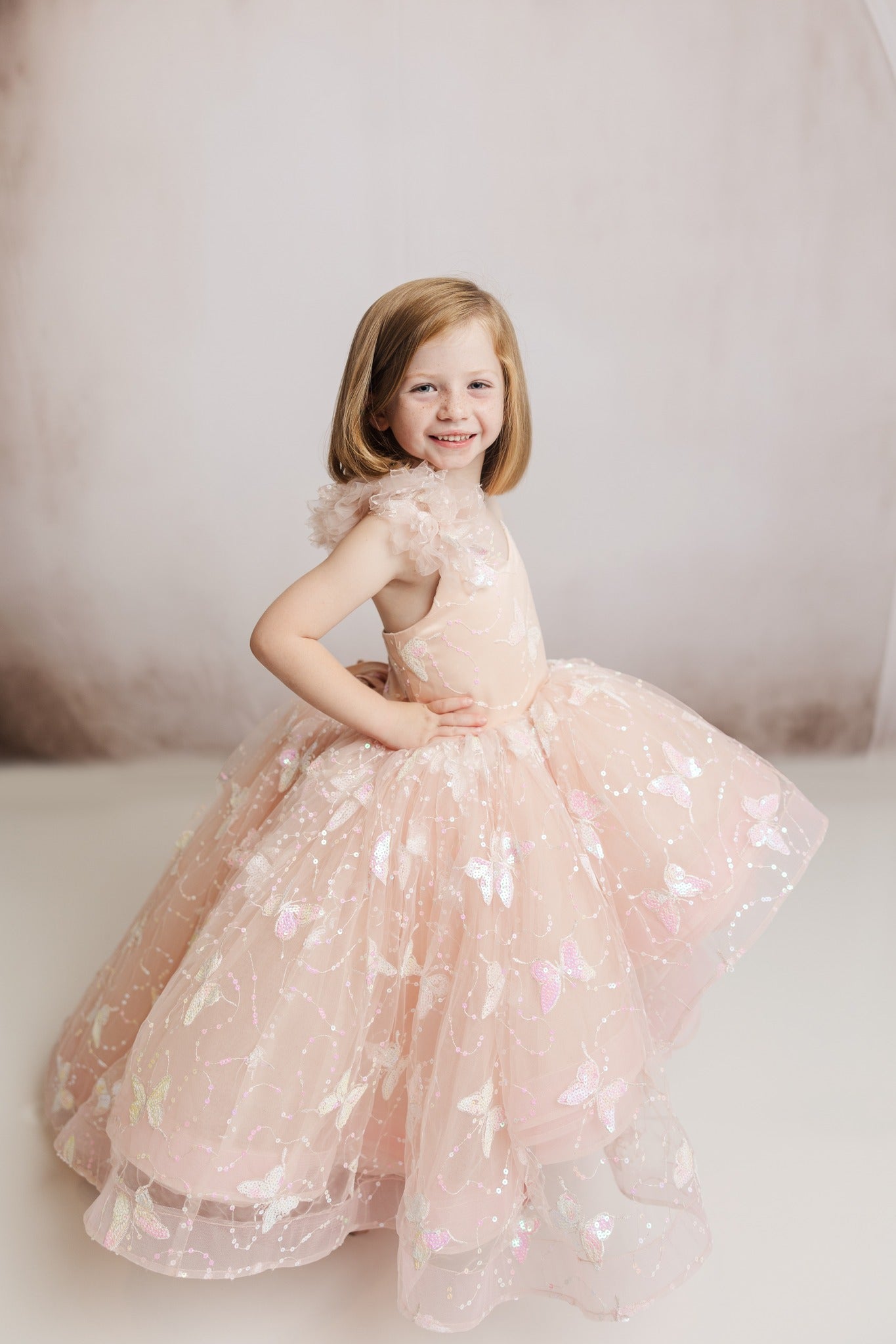 "The Anastasia high-low gown, featuring a stunning 3D sequin embroidered butterfly fabric and a one-shoulder ruffle detail."