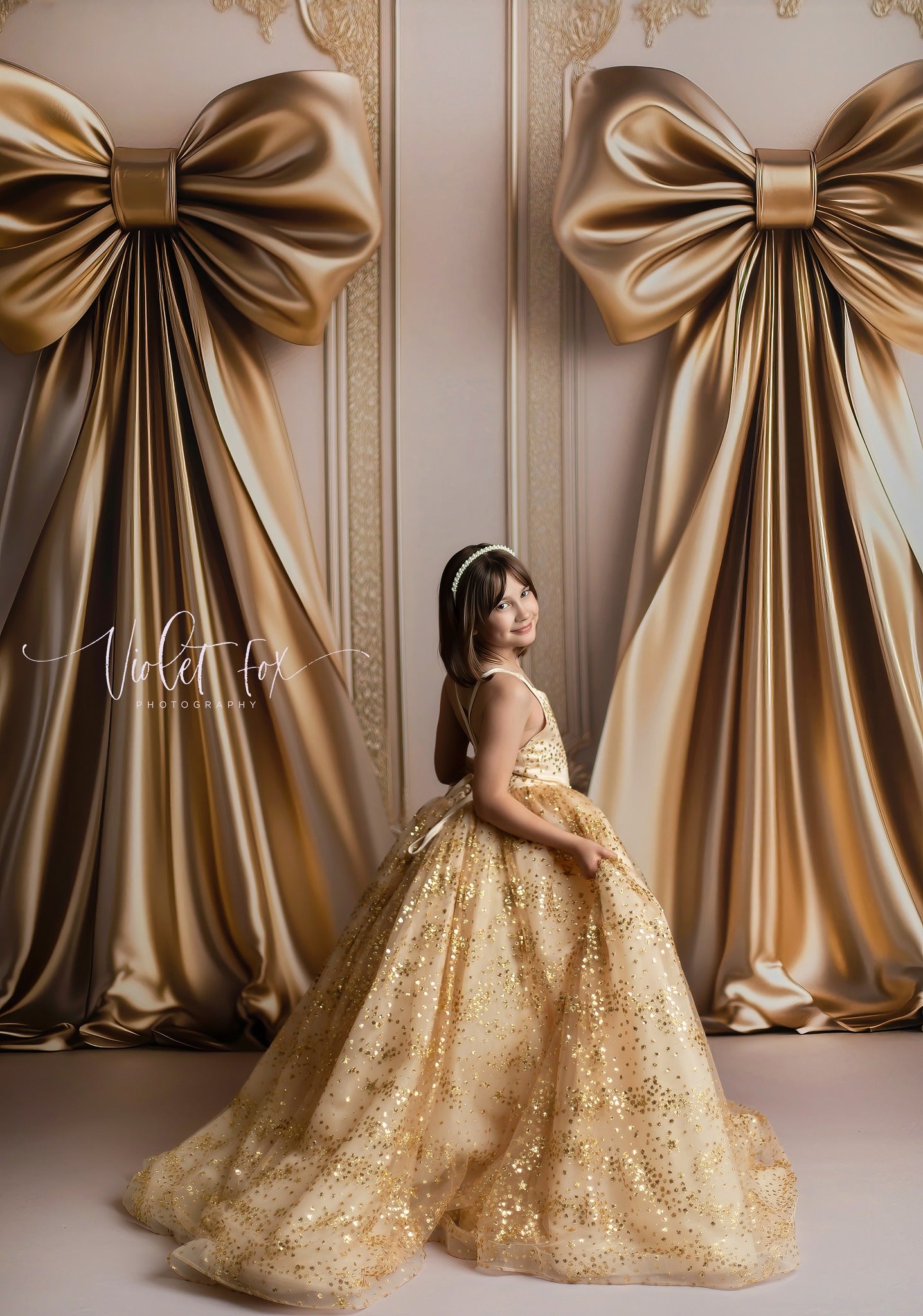 Child posing in floor-length gold star gown under studio lights