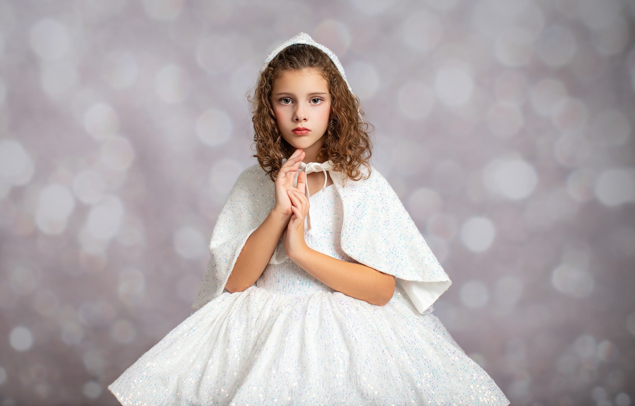 Young girl in a white dress with a hood against a blurred background