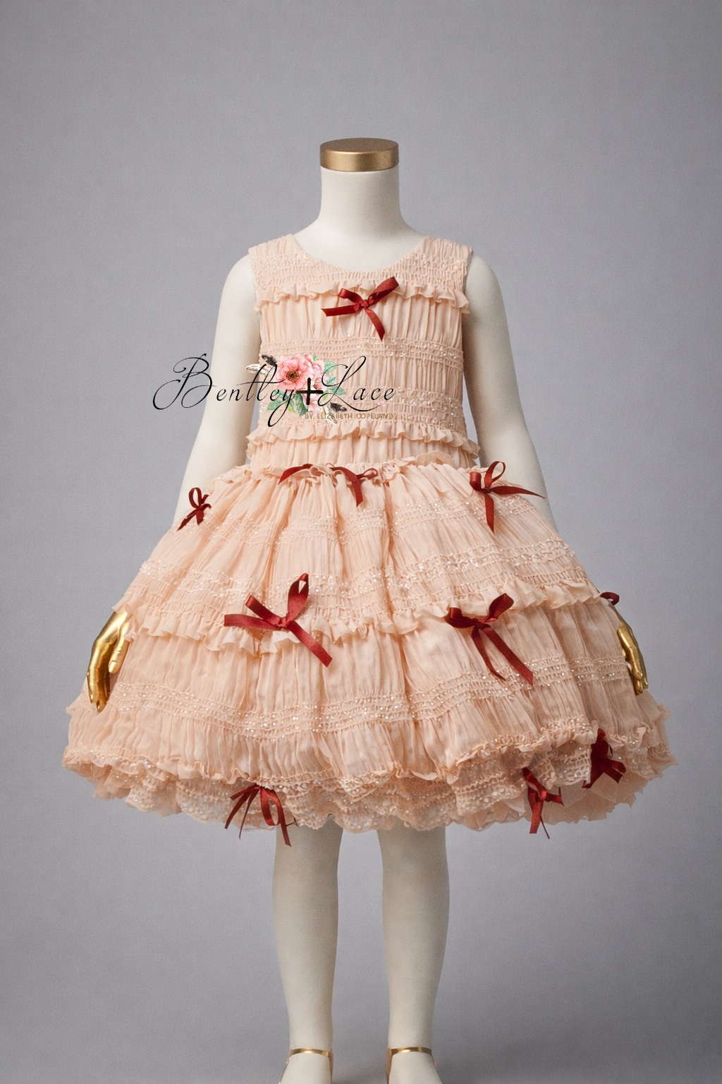 Pink dress with red bows on a mannequin against a gray background