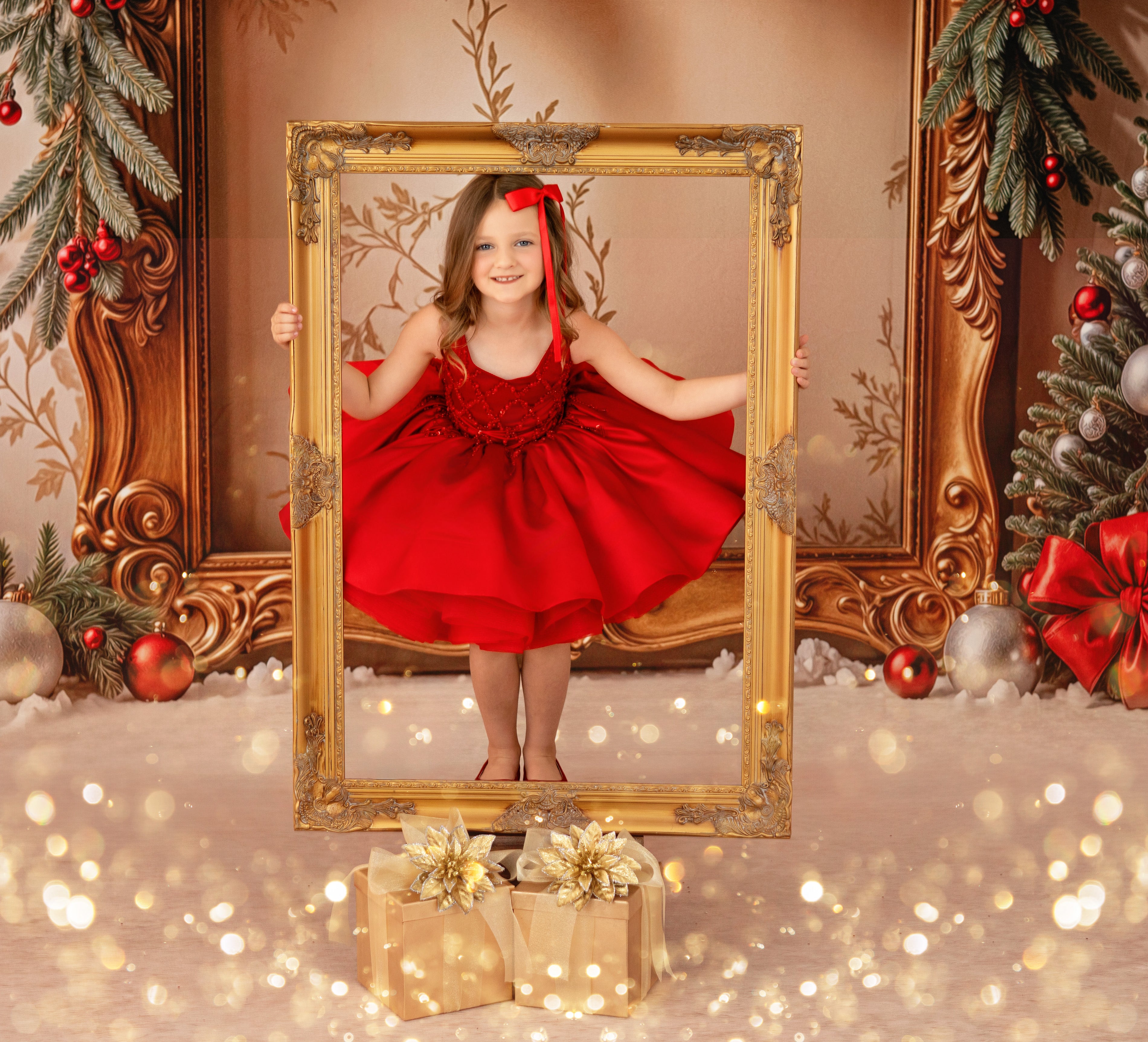 Young girl in a red dress standing in front of a gold frame with Christmas decorations around.