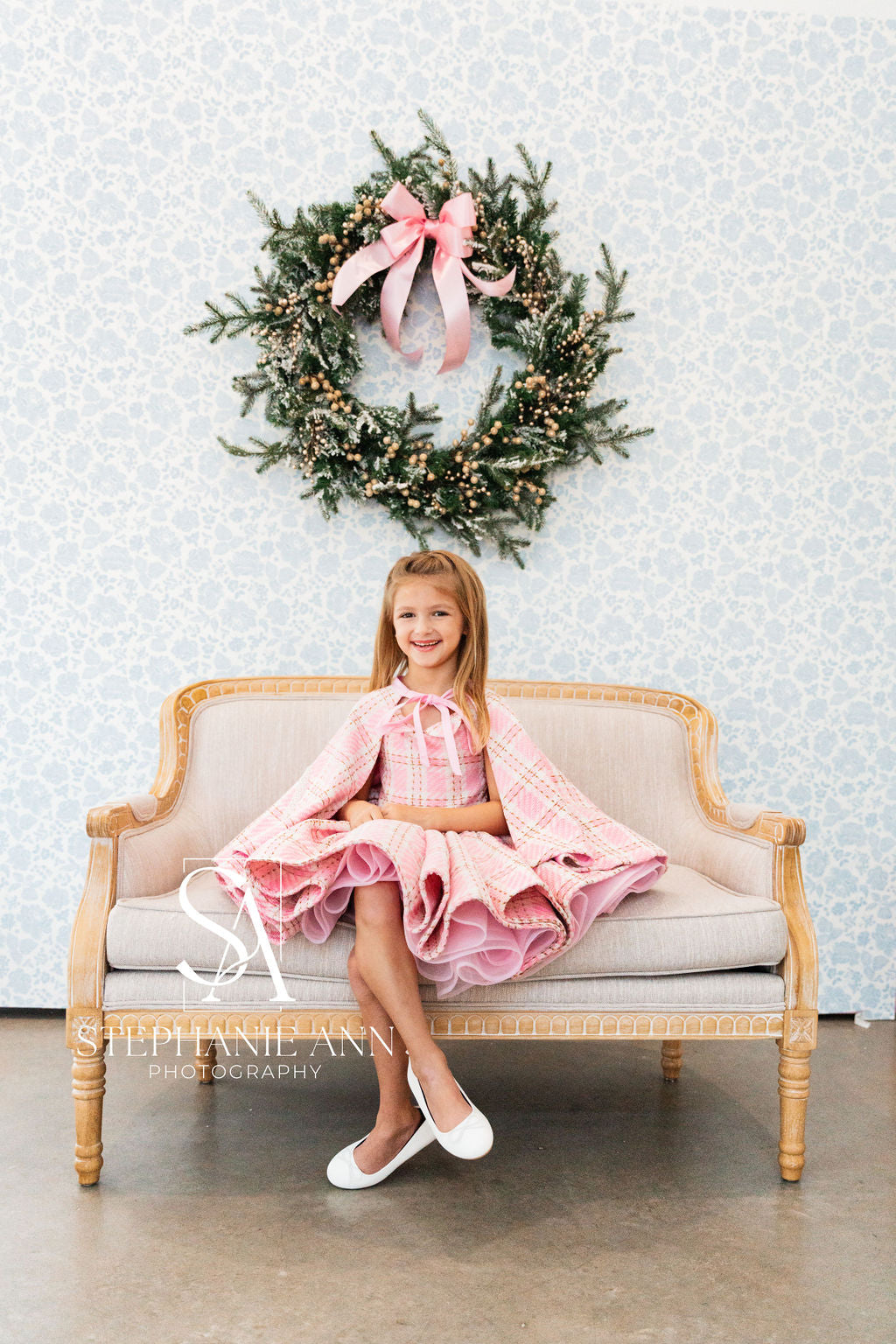 Girl dressed in a cute pink wool plaid dress, showing off its classic plaid pattern.