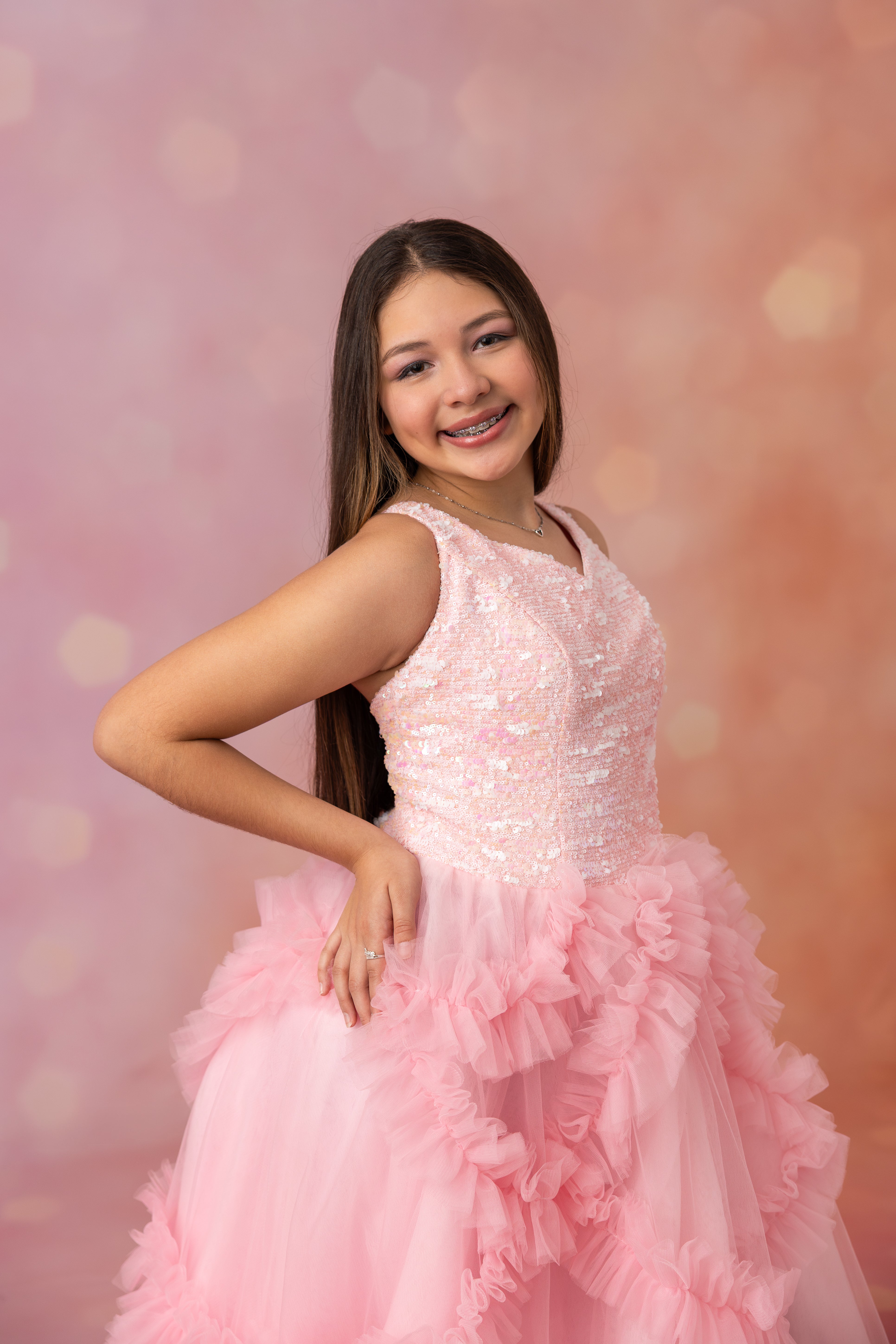 Young girl in a pink sequined dress with a blurred pink background
