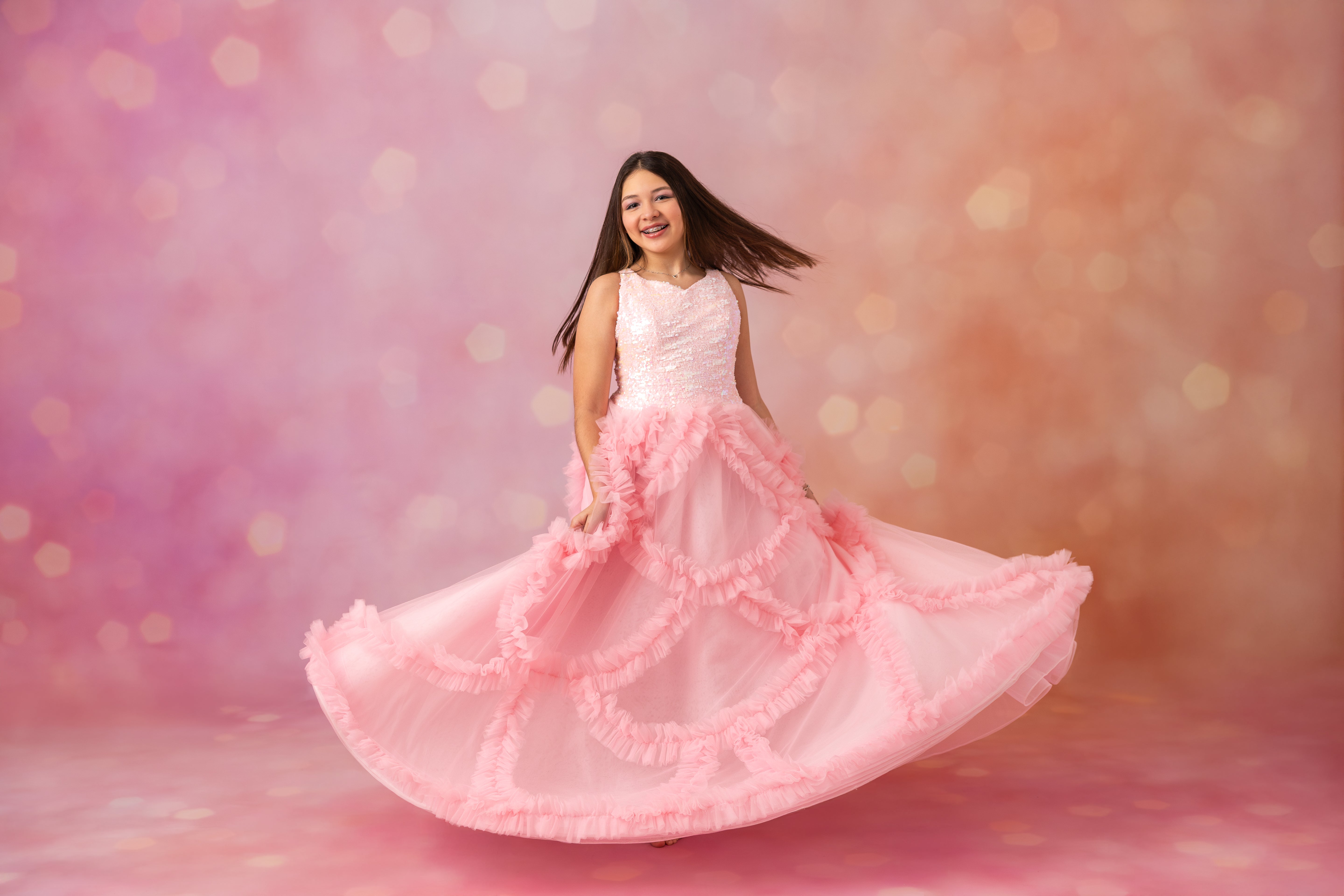 Woman in a pink dress with ruffles on a soft pink background