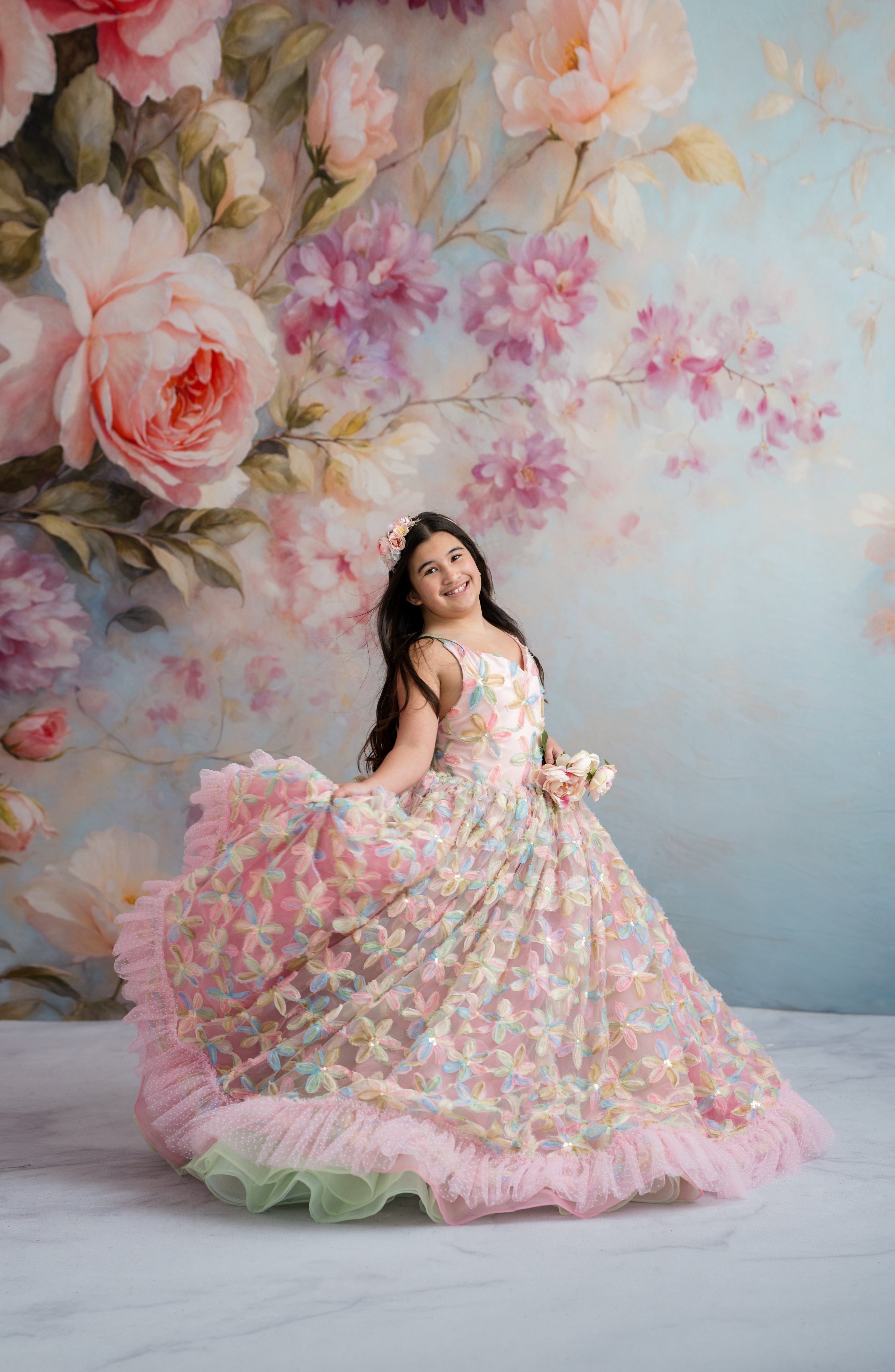 Young girl in a floral dress standing in front of a floral backdrop
