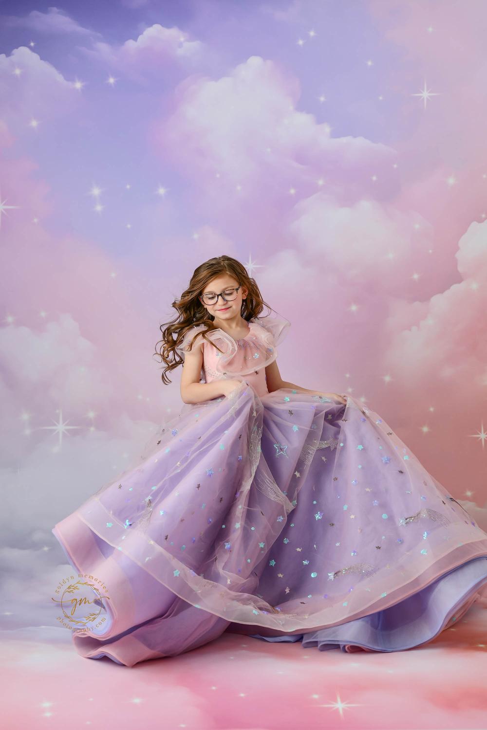 "A smiling girl wearing glasses, posing gracefully in an ethereal pink and purple gown with celestial details."