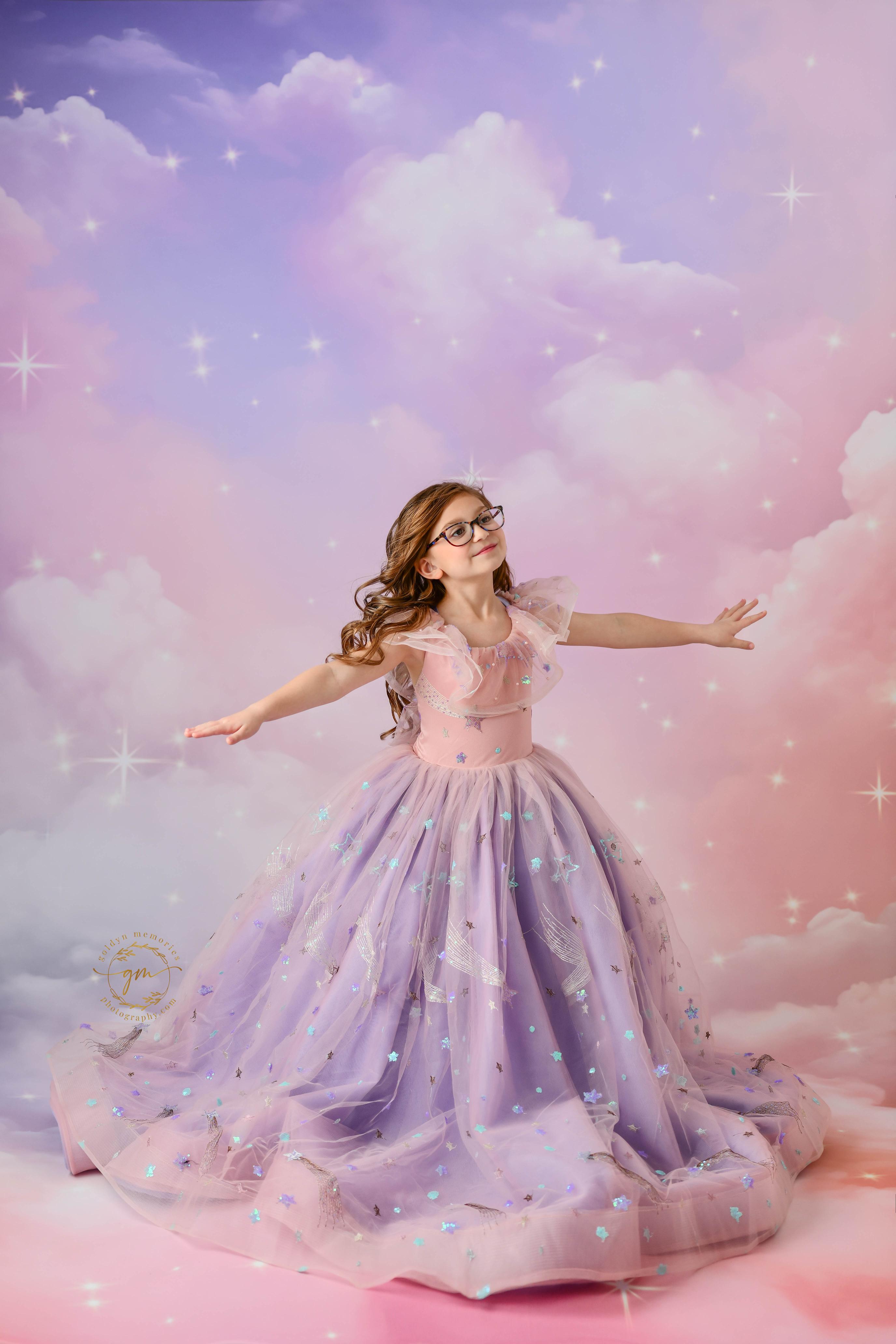 "A girl in a glittering pink and purple gown, styled with delicate star decorations, posing with elegance in a dreamy setting."