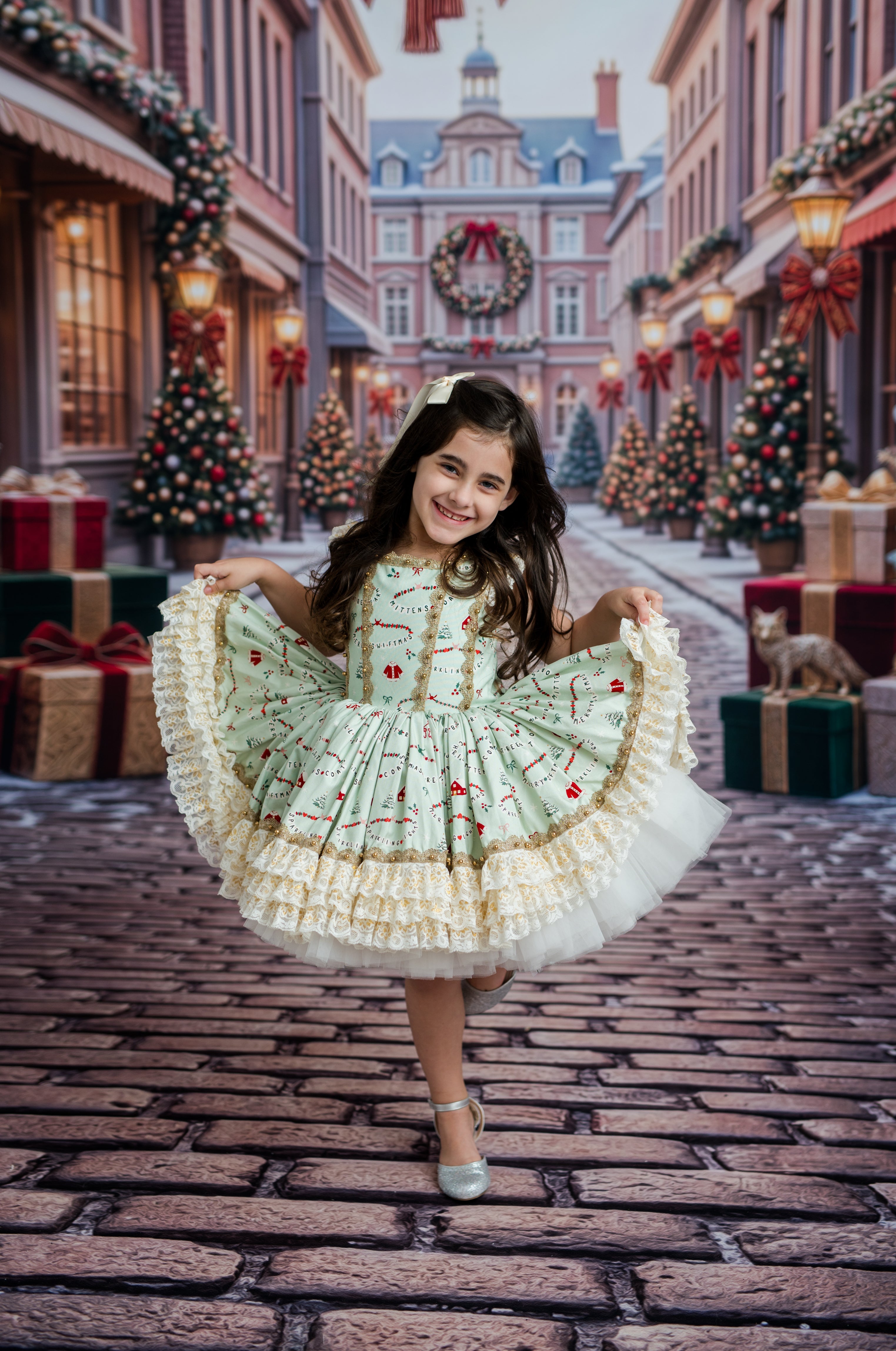 A young girl twirling in a festive Christmas dress on a cobblestone street decorated with trees, wreaths, and gift boxes.