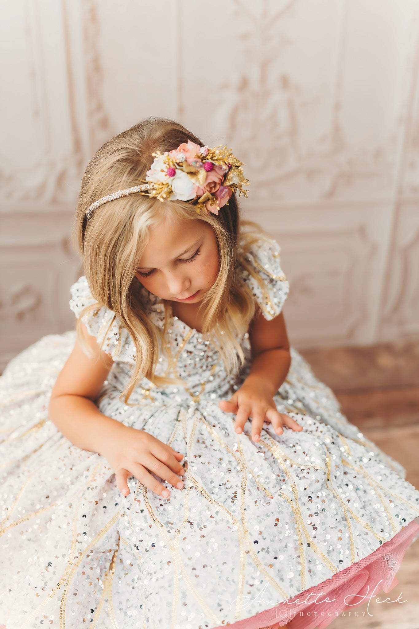 Little girl wearing a festive dress with a bright pink underskirt, captured mid-twirl, her gold shoes adding a touch of elegance.