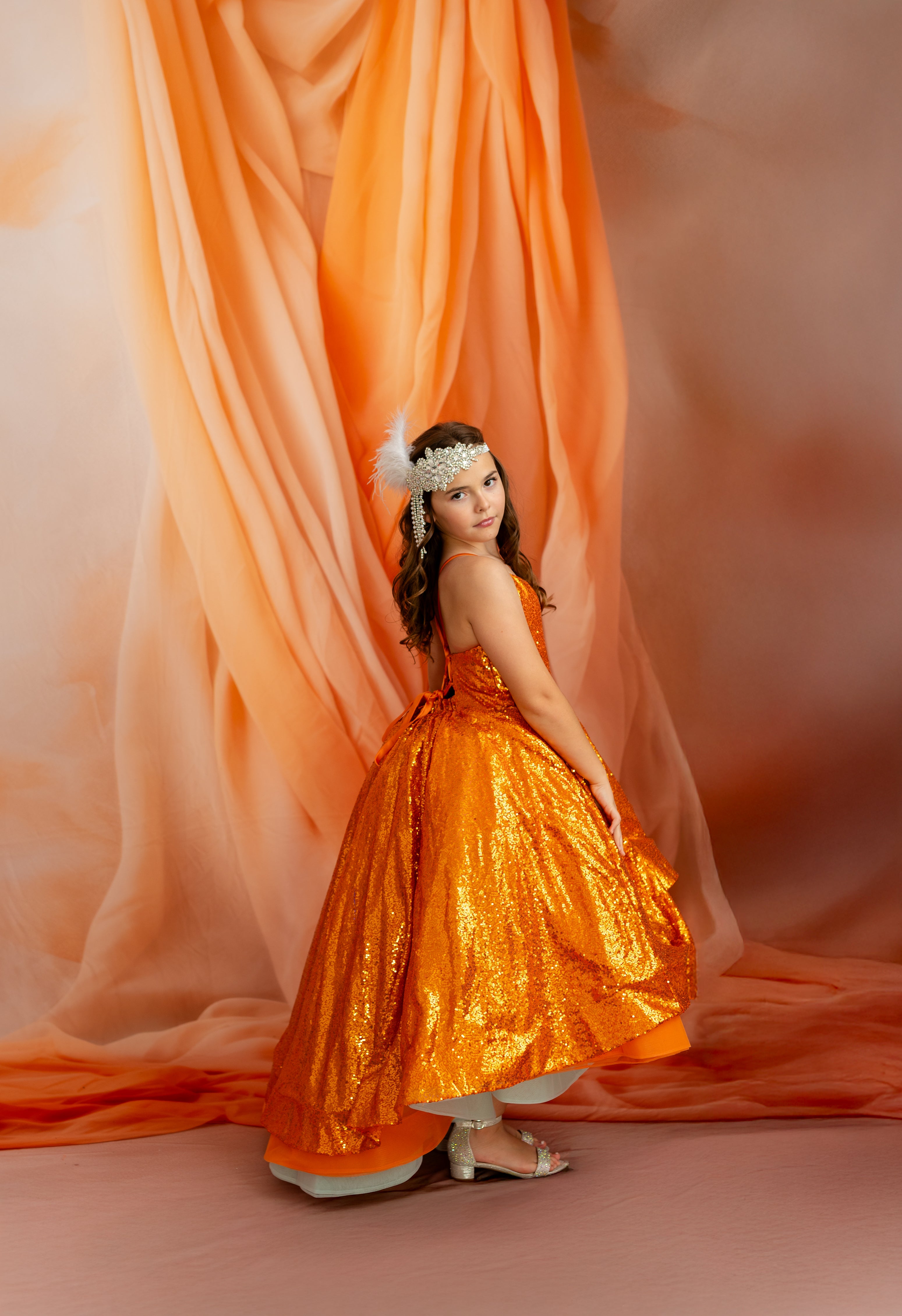 Woman in an orange dress standing in front of orange fabric