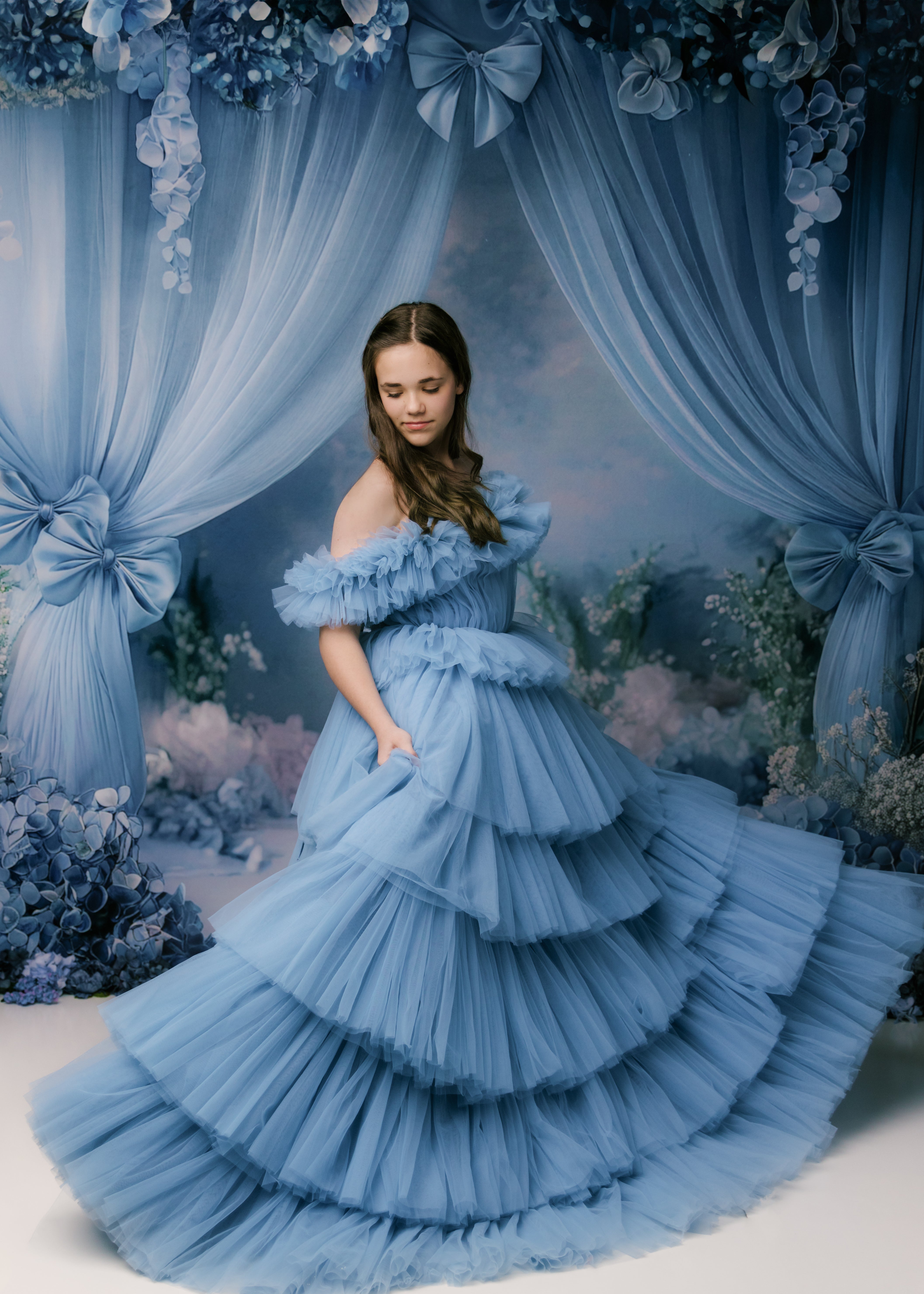 Young woman wearing a floor-length bluet gown with intricate lace detailing.