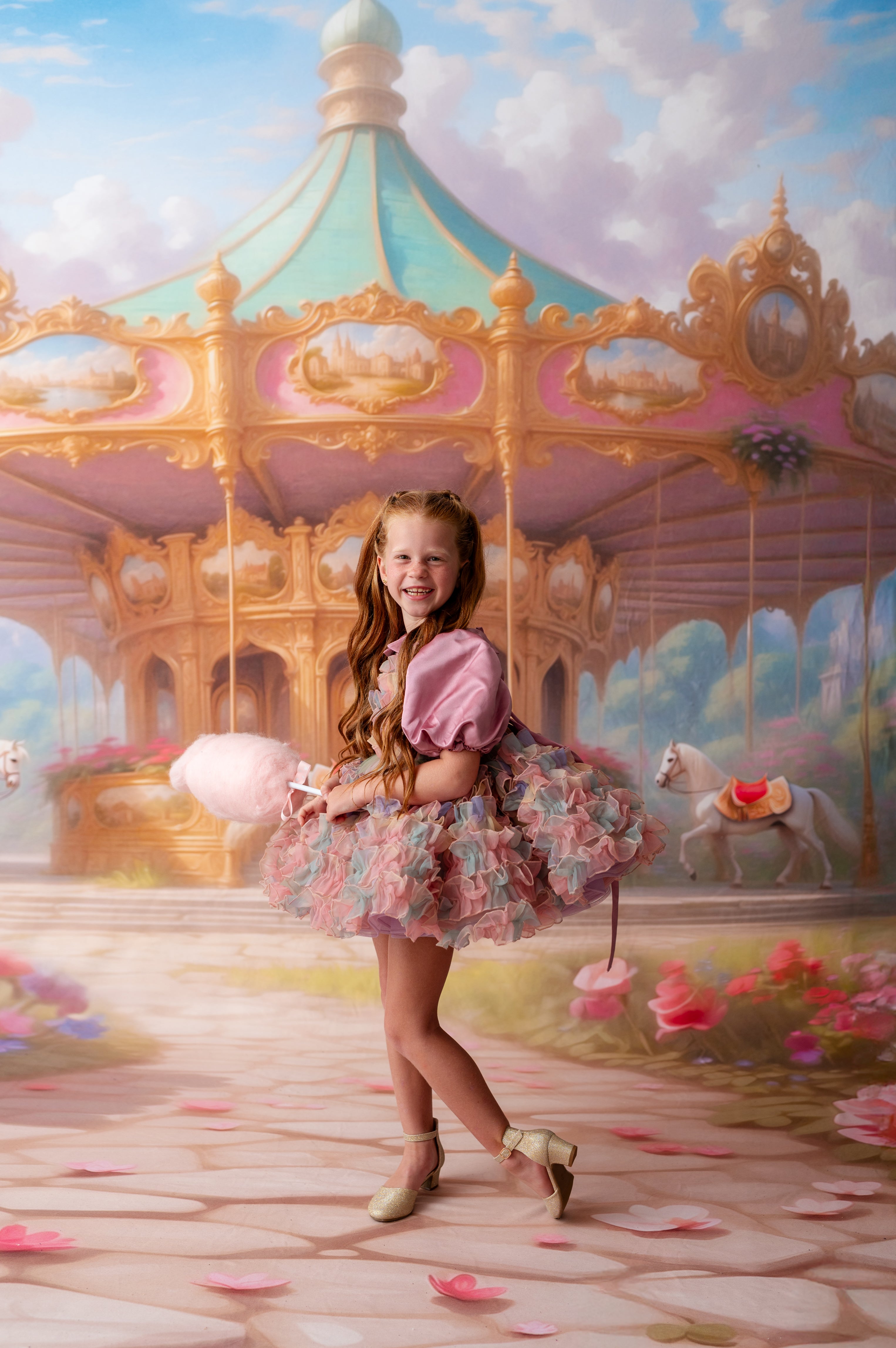 Young girl in a pink dress standing in front of a carousel painting