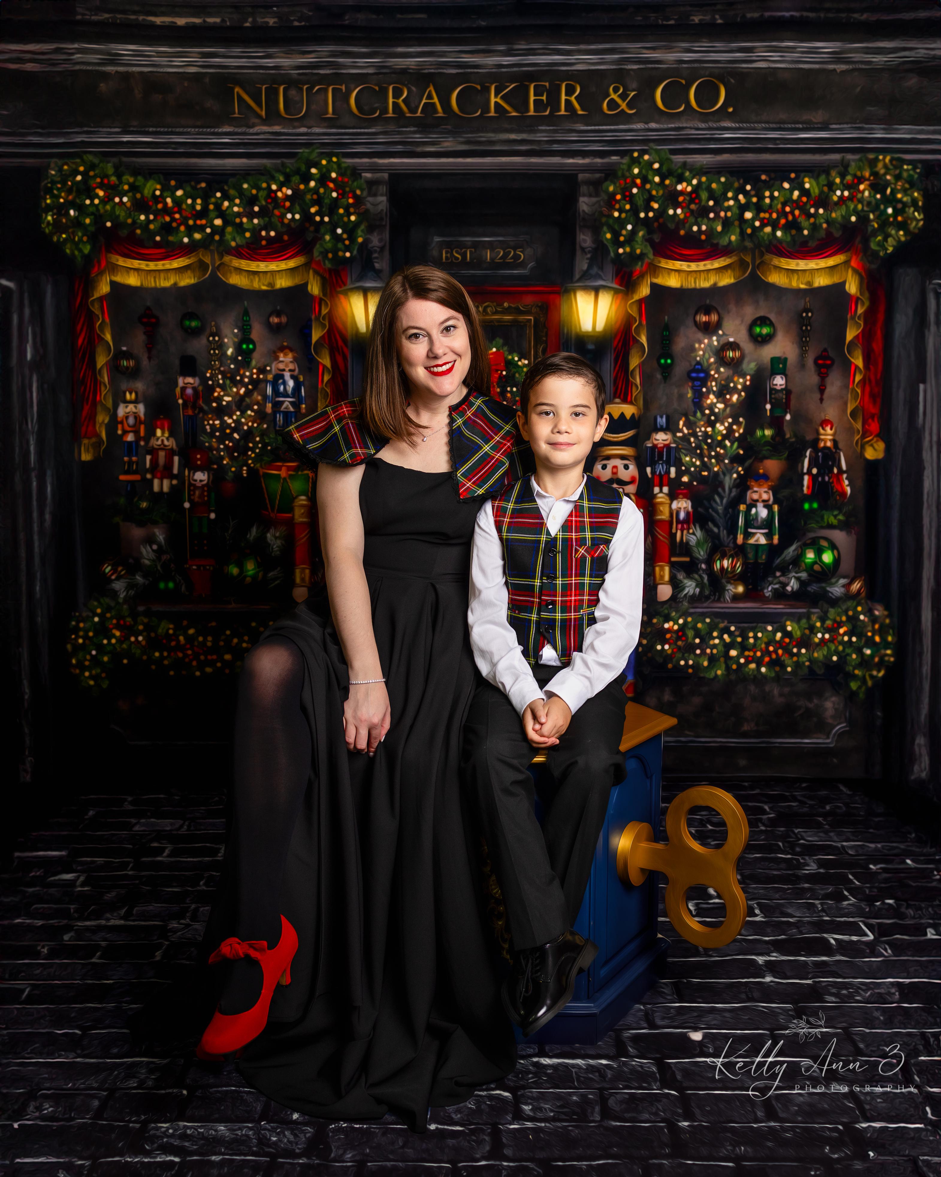 Two people posing in front of a Nutcracker & Co. themed backdrop with decorative lights and ornaments.