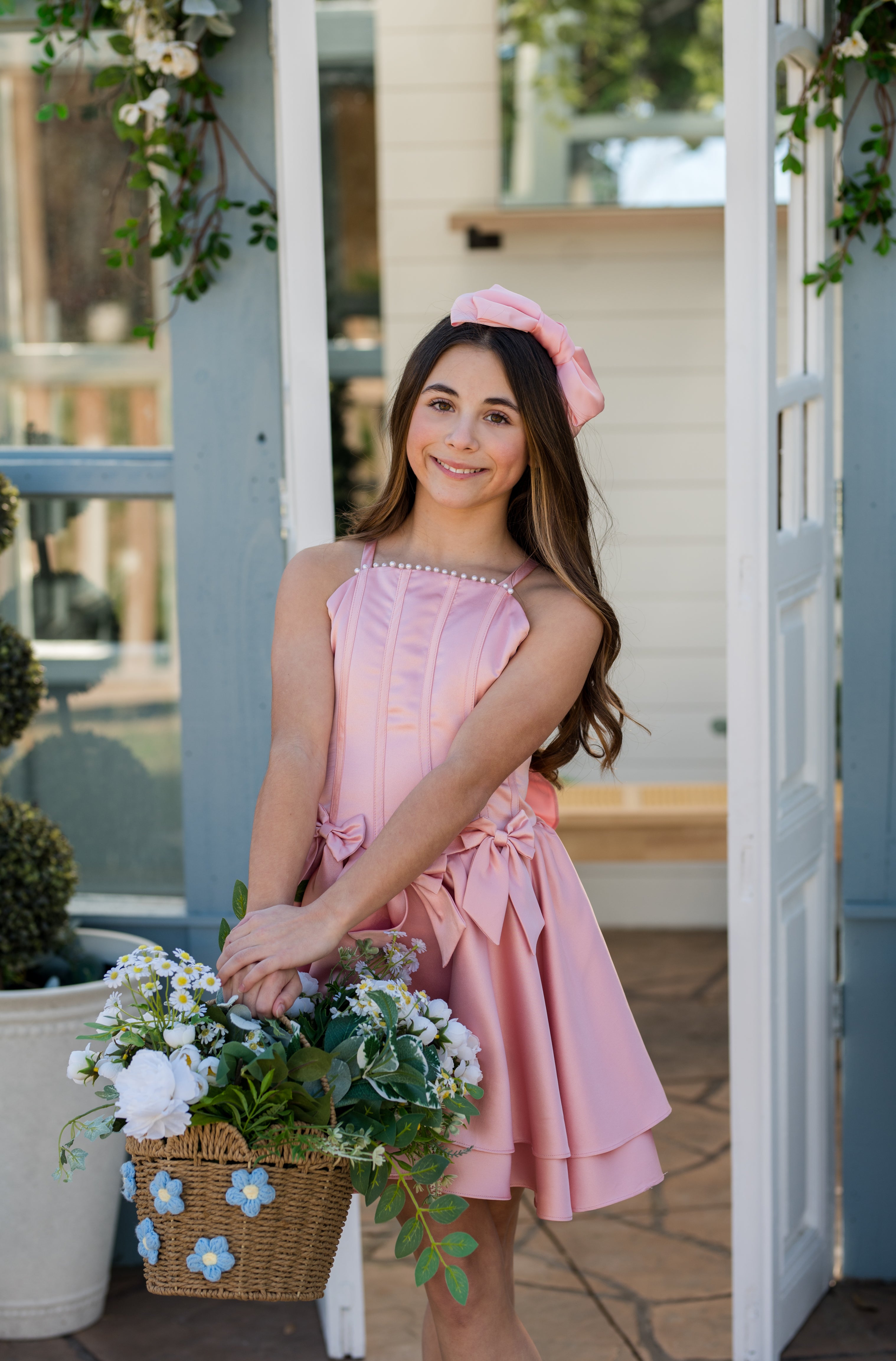 Woman in a pink dress holding flowers on a porch