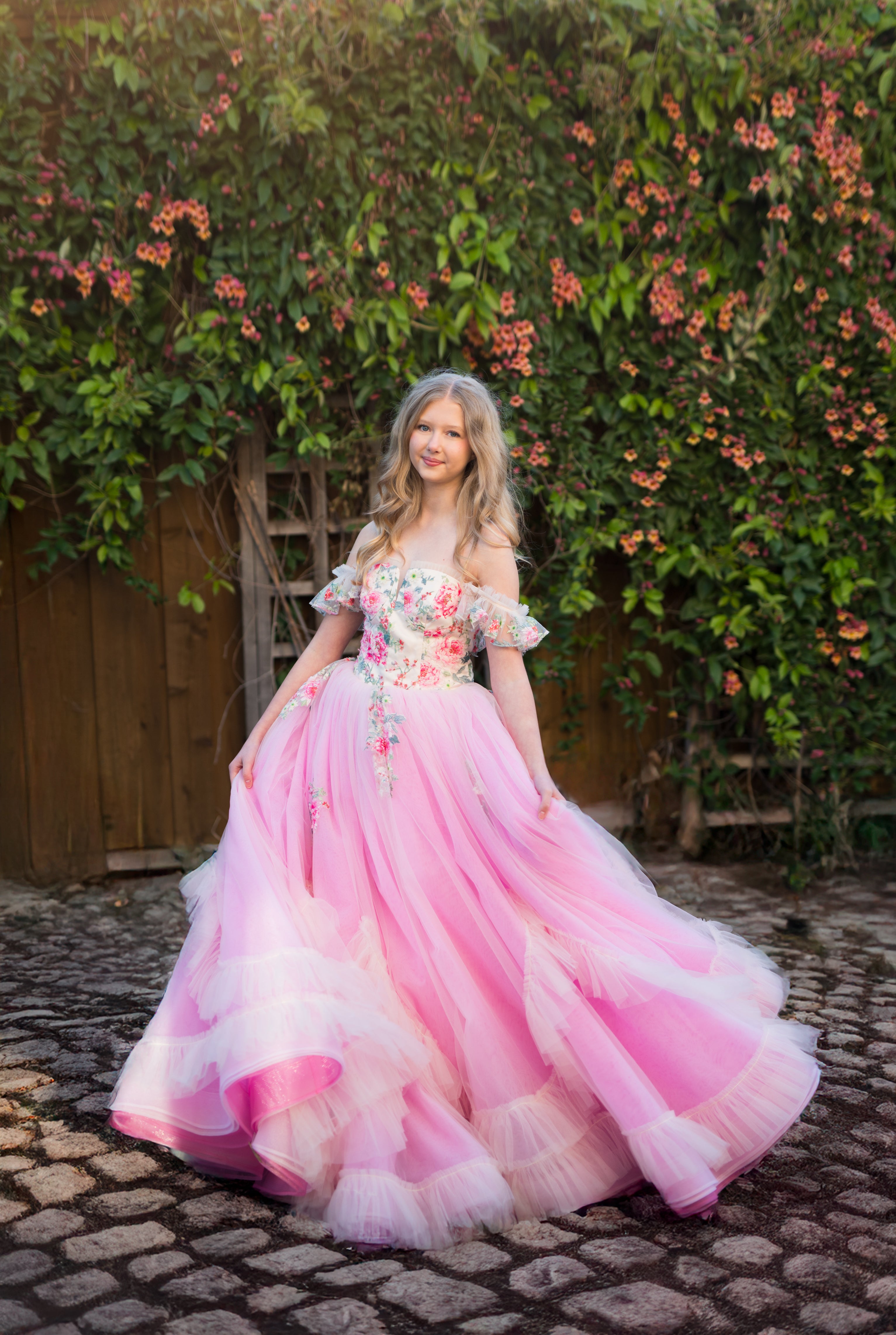 Woman in a pink floral dress standing in front of greenery