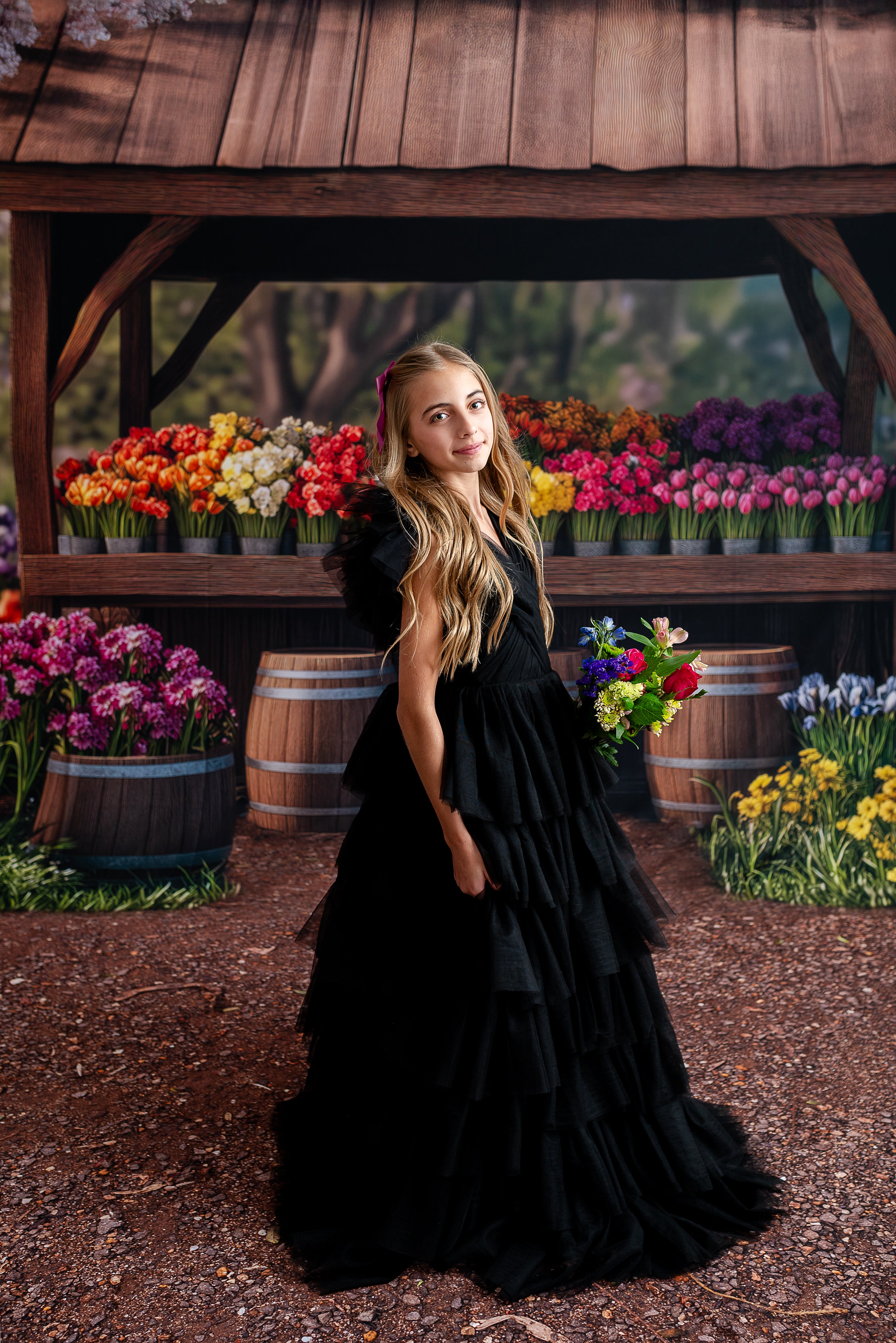A teen model wearing the Noir Reverie black tulle gown with layered ruffles in a formal setting.