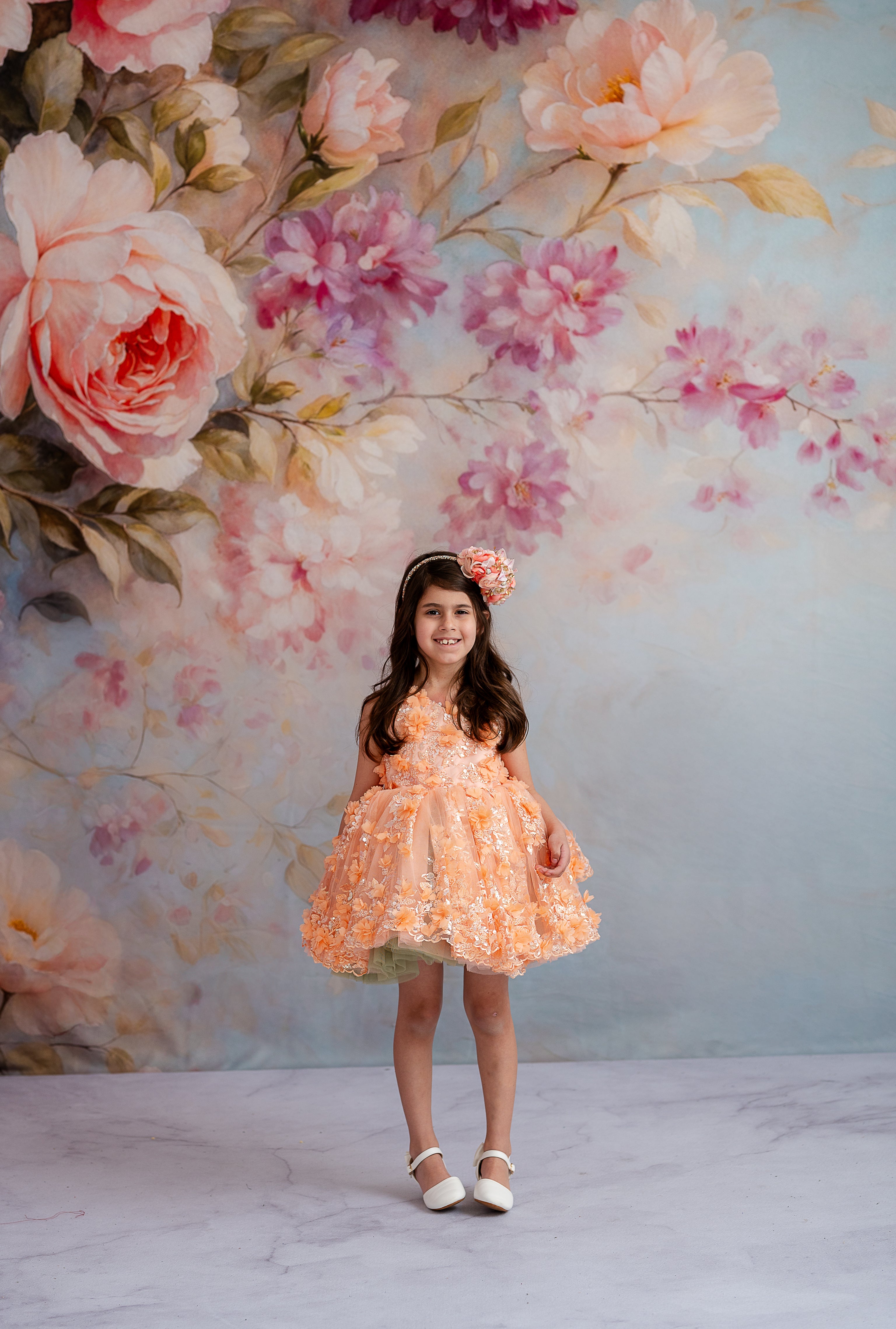girl wearing a vintage dress with soft peach tones, floral embroidery, and petal-length skirt.