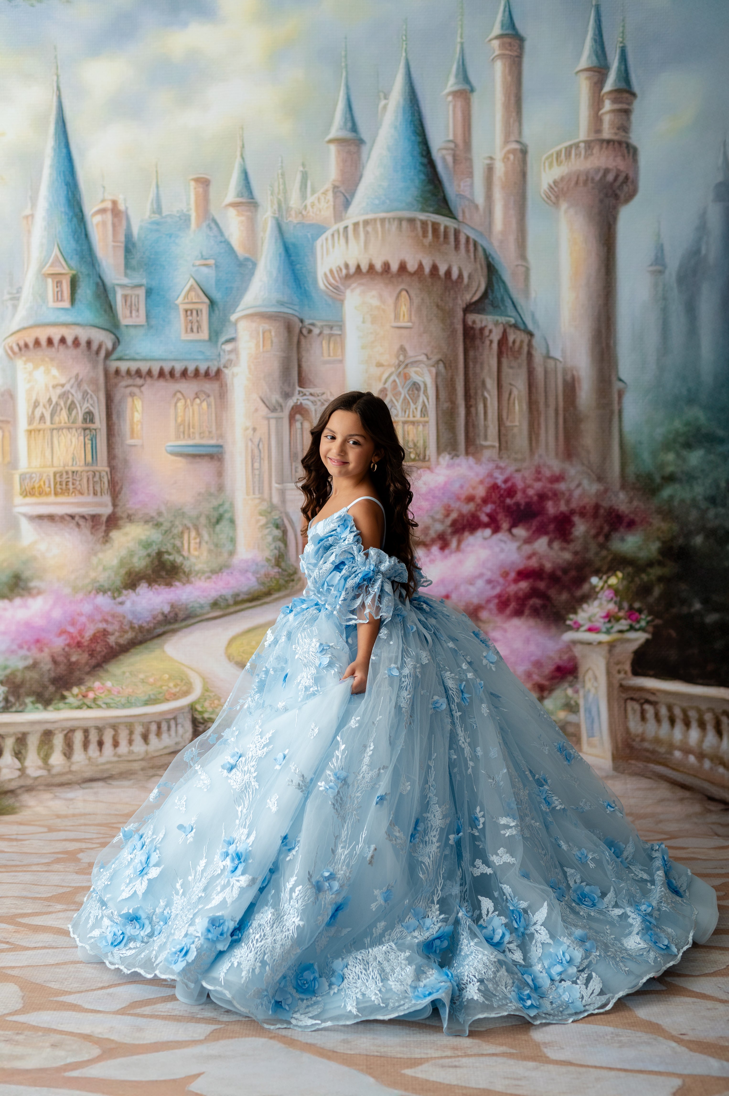 Young girl in a blue dress standing in front of a fairy-tale castle.