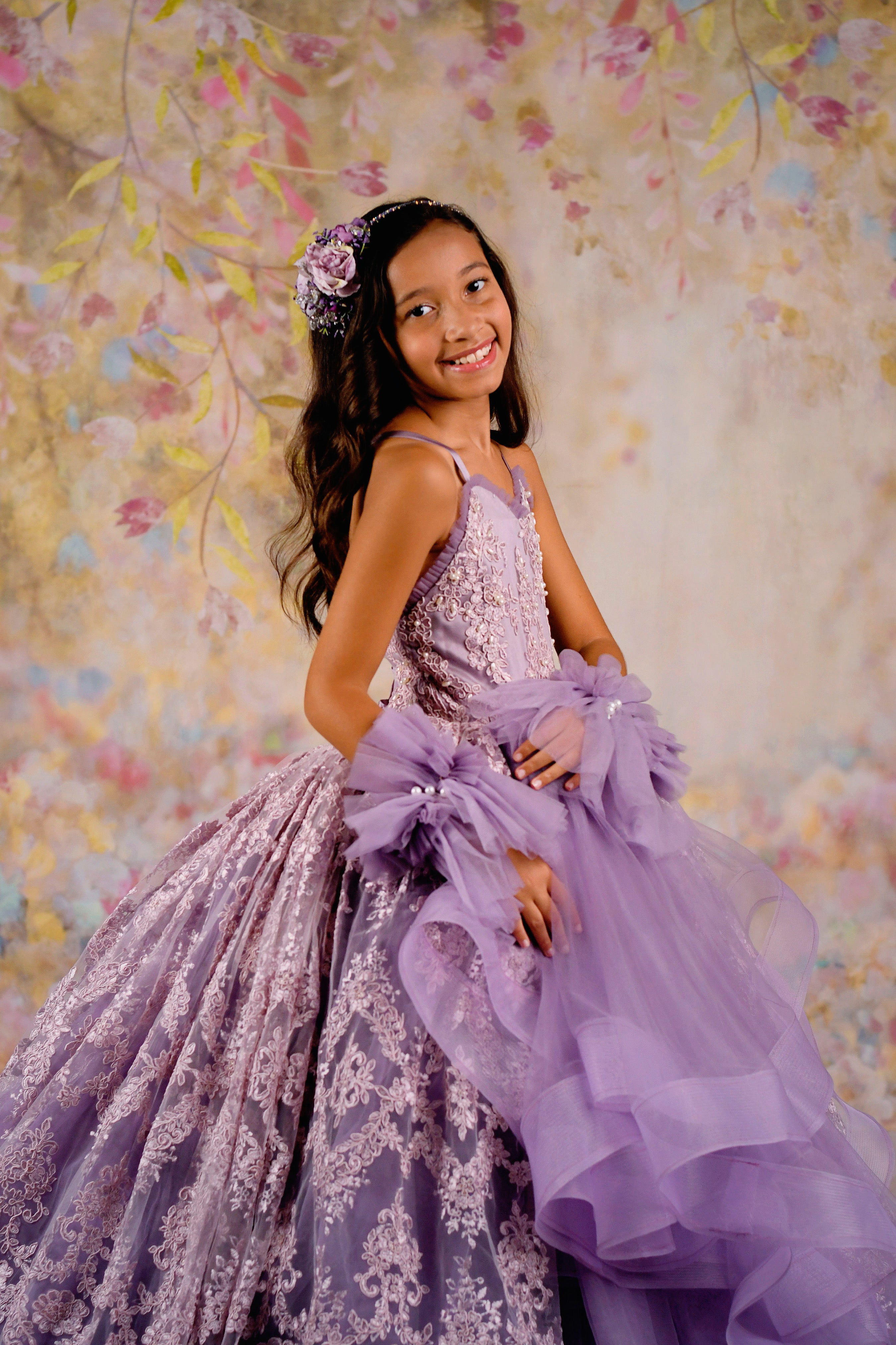 A detailed shot of a lavender gown showcasing delicate lace appliqués, cascading tulle layers, and whimsical bow embellishments.
