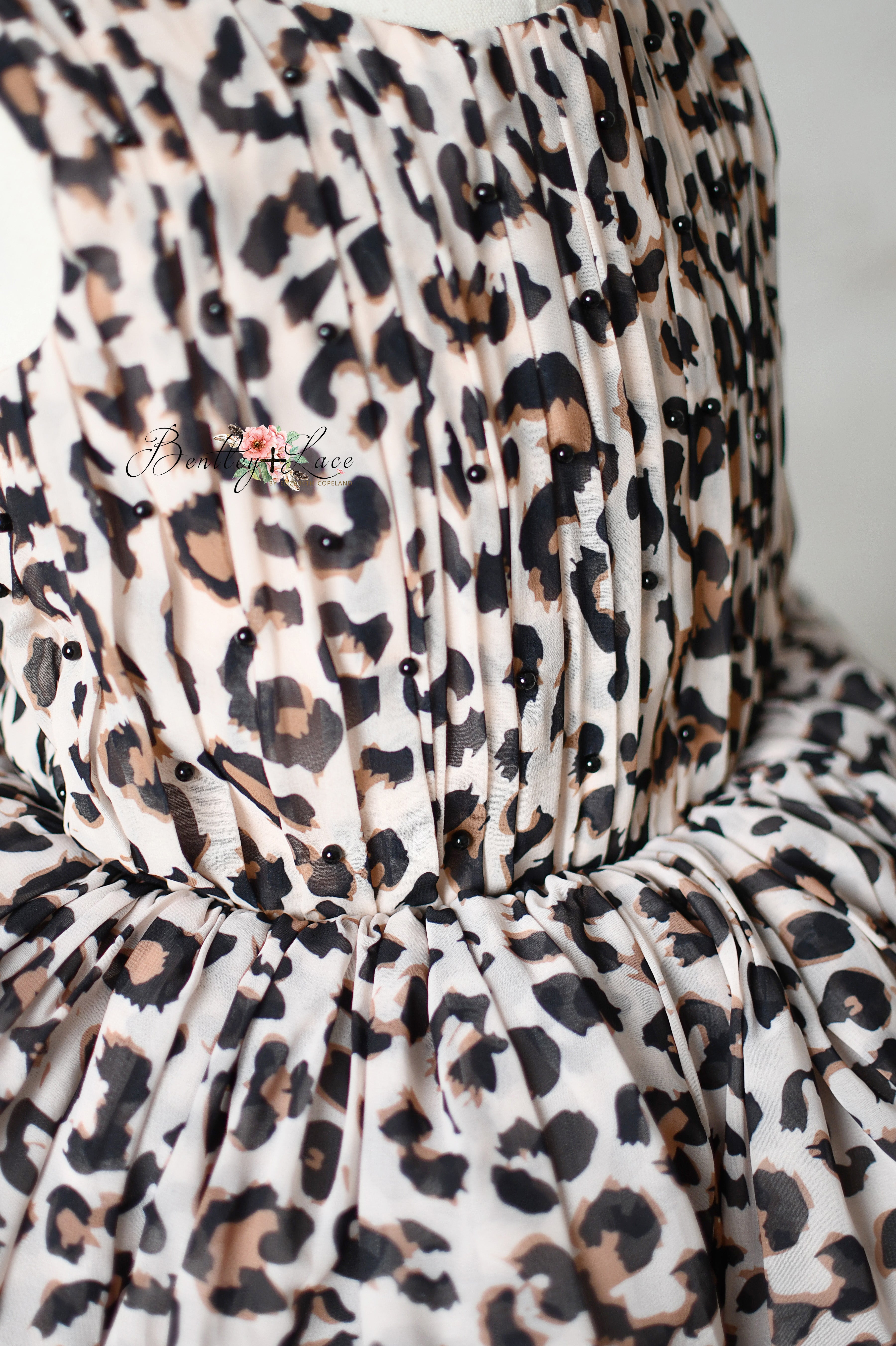 "Back view of a leopard print dress with tie-back details and elastic waist."