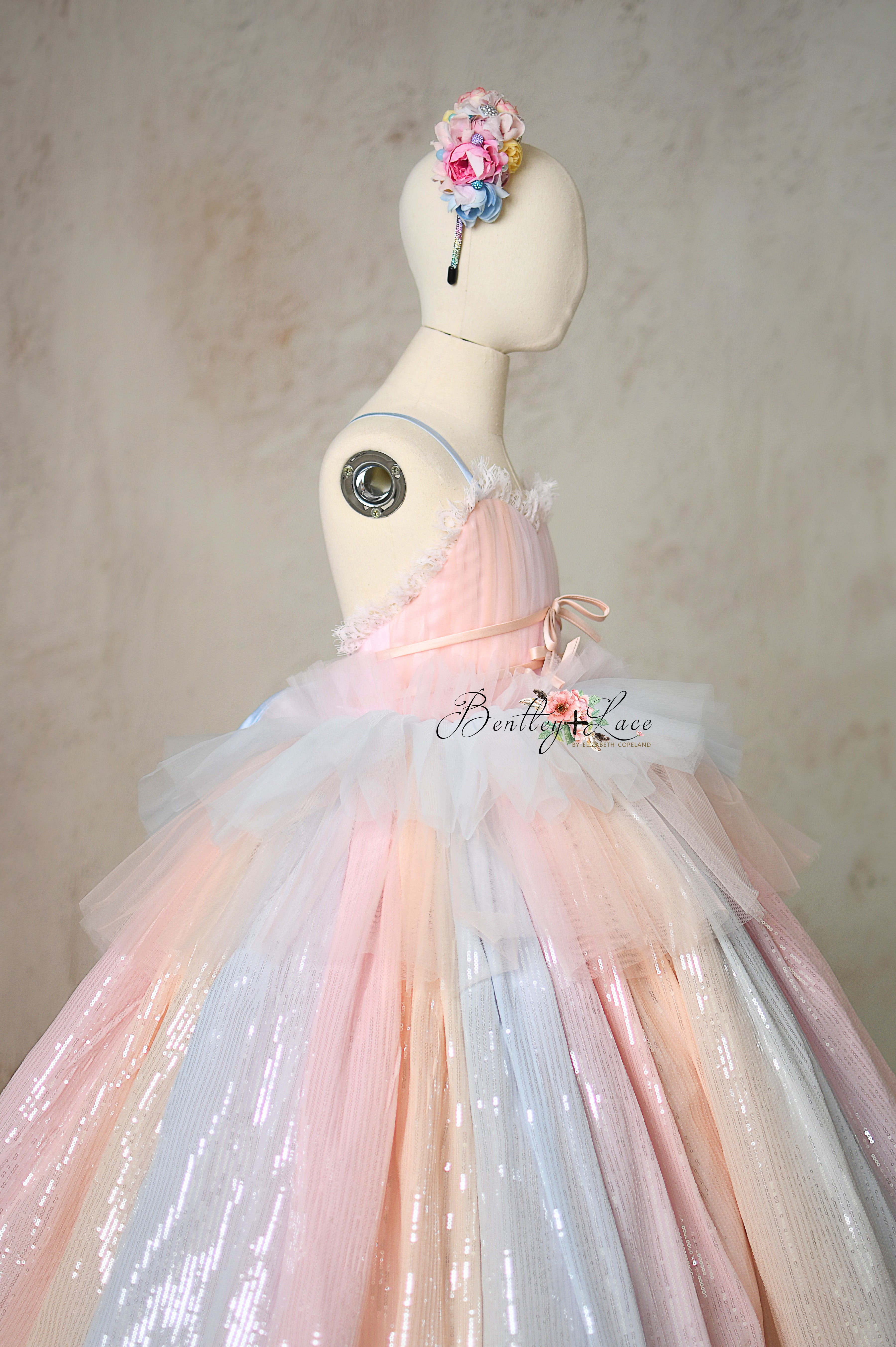 Dreamy tulle gown in blush, ivory, and gray with delicate bow details.