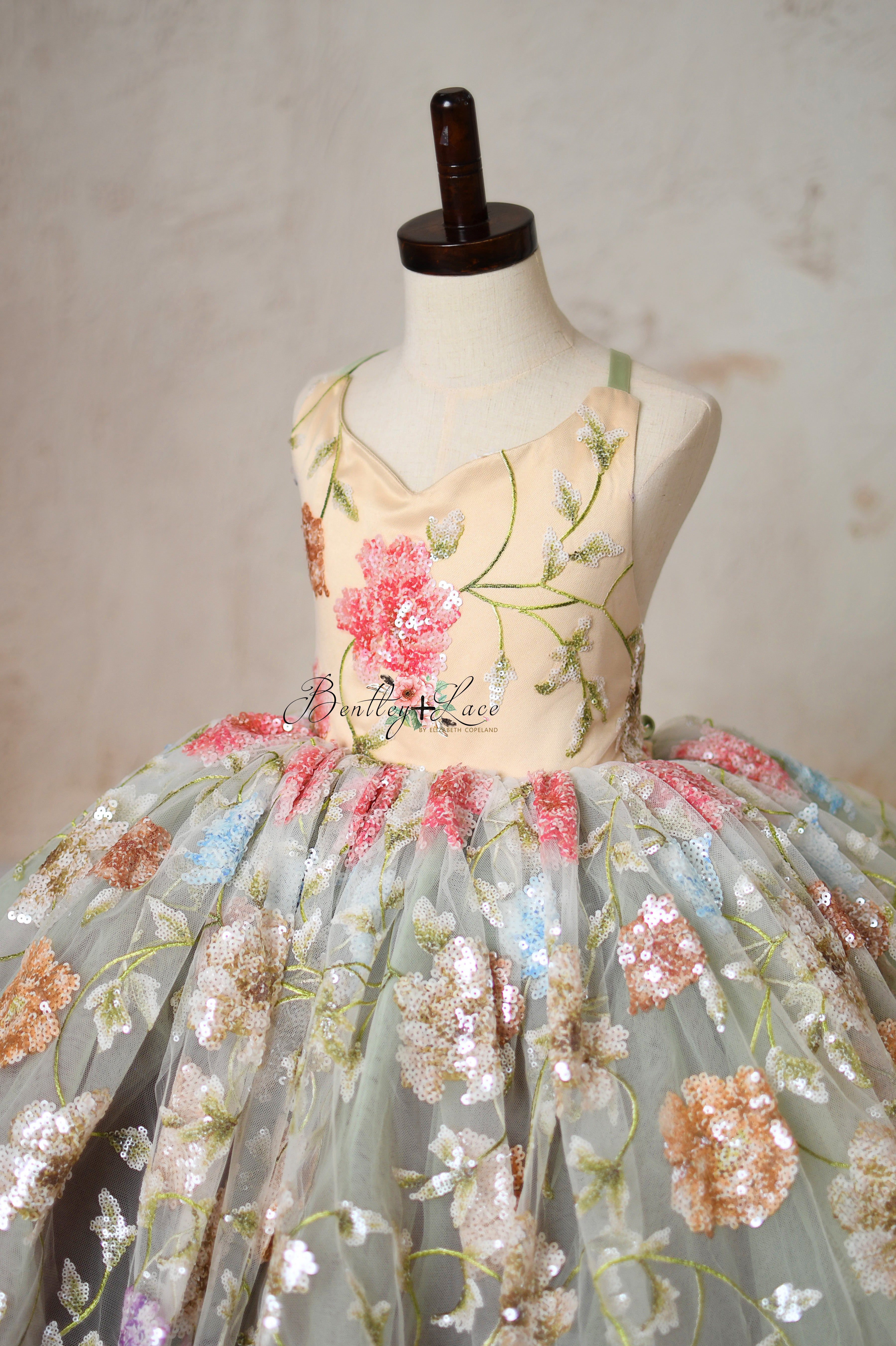 Green and pastel flower girl dress with sparkling sequin accents.