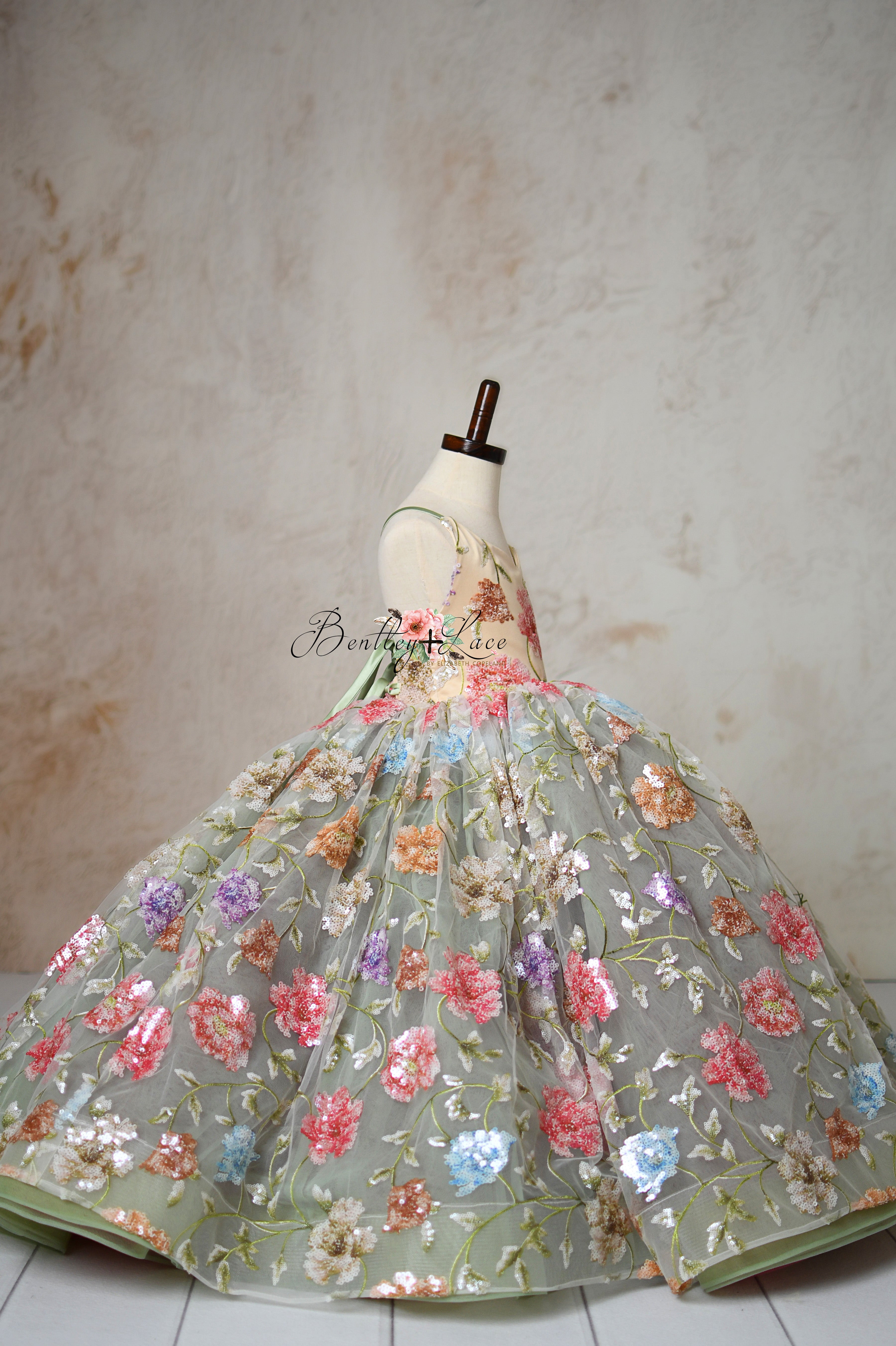 Mannequin showcasing a glittering flower girl dress with vibrant hues.