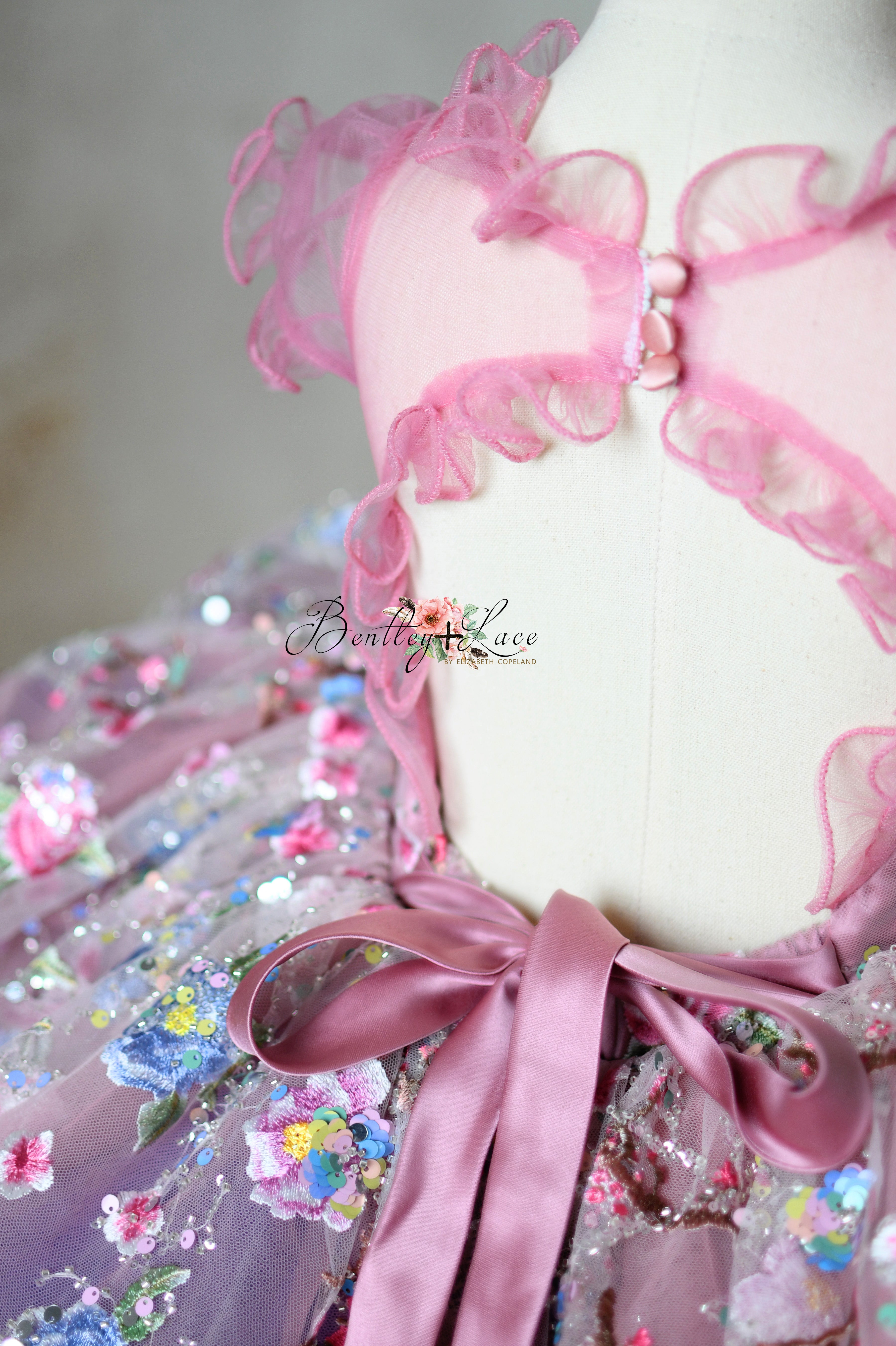Detailed shot of the faux button at the neckline and the elastic waist of the dress.