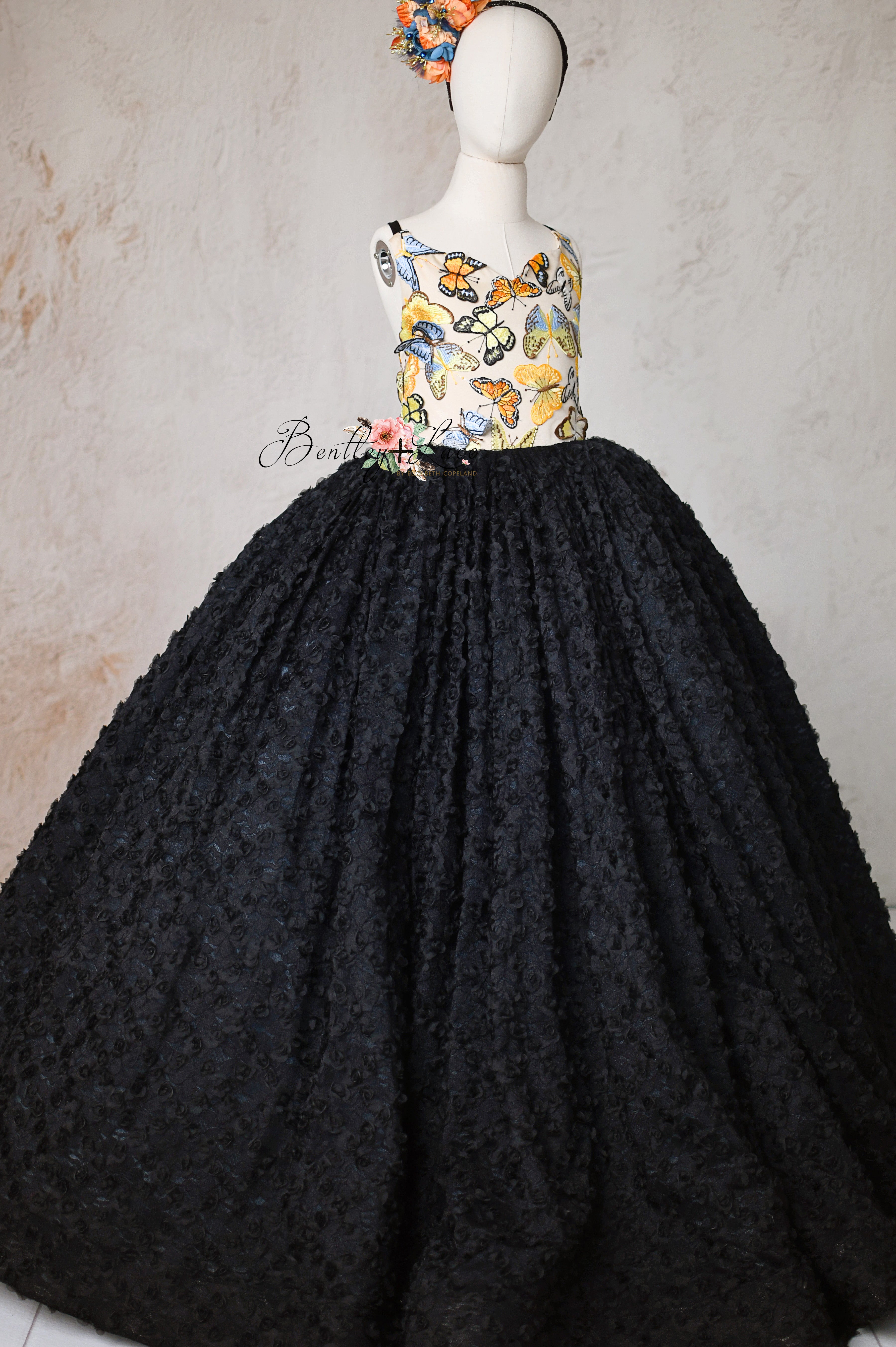 Floor-length butterfly gown for girls with a vibrant bodice and dramatic black skirt.
