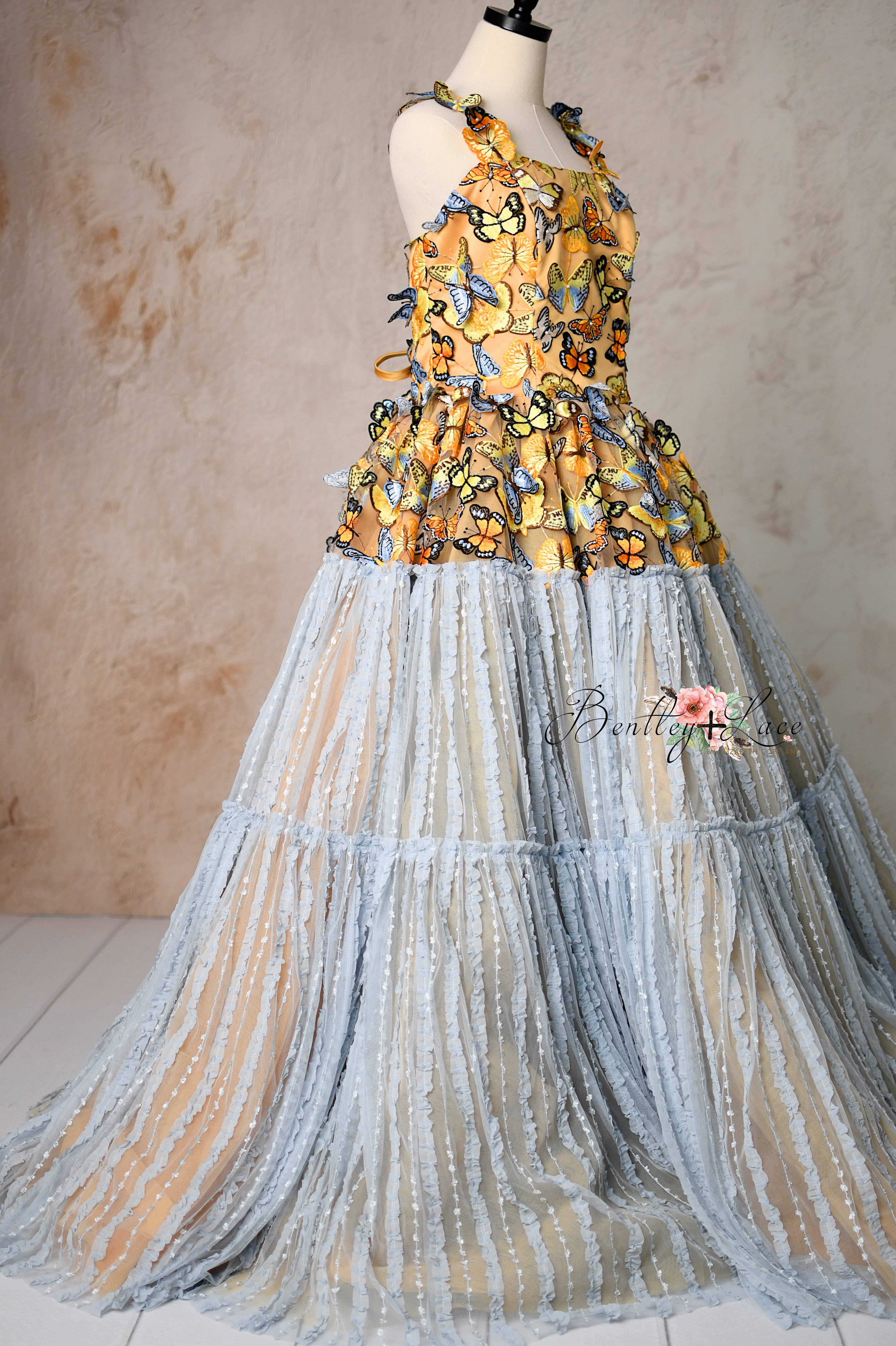 Elegant full-length dress with intricate butterfly details and a soft blue tulle skirt.