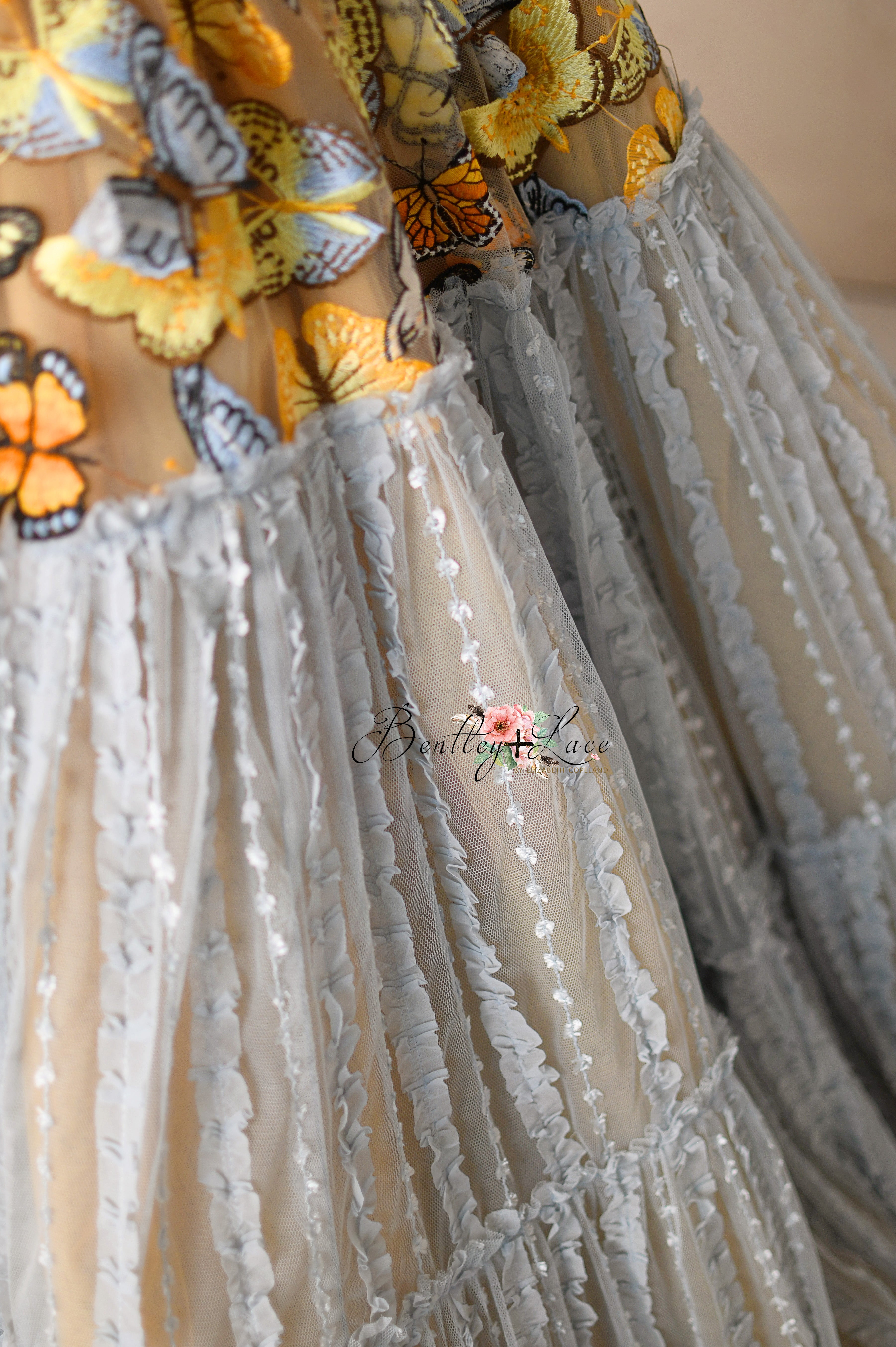 A fairytale gown featuring a vibrant butterfly motif and flowing pastel textures.