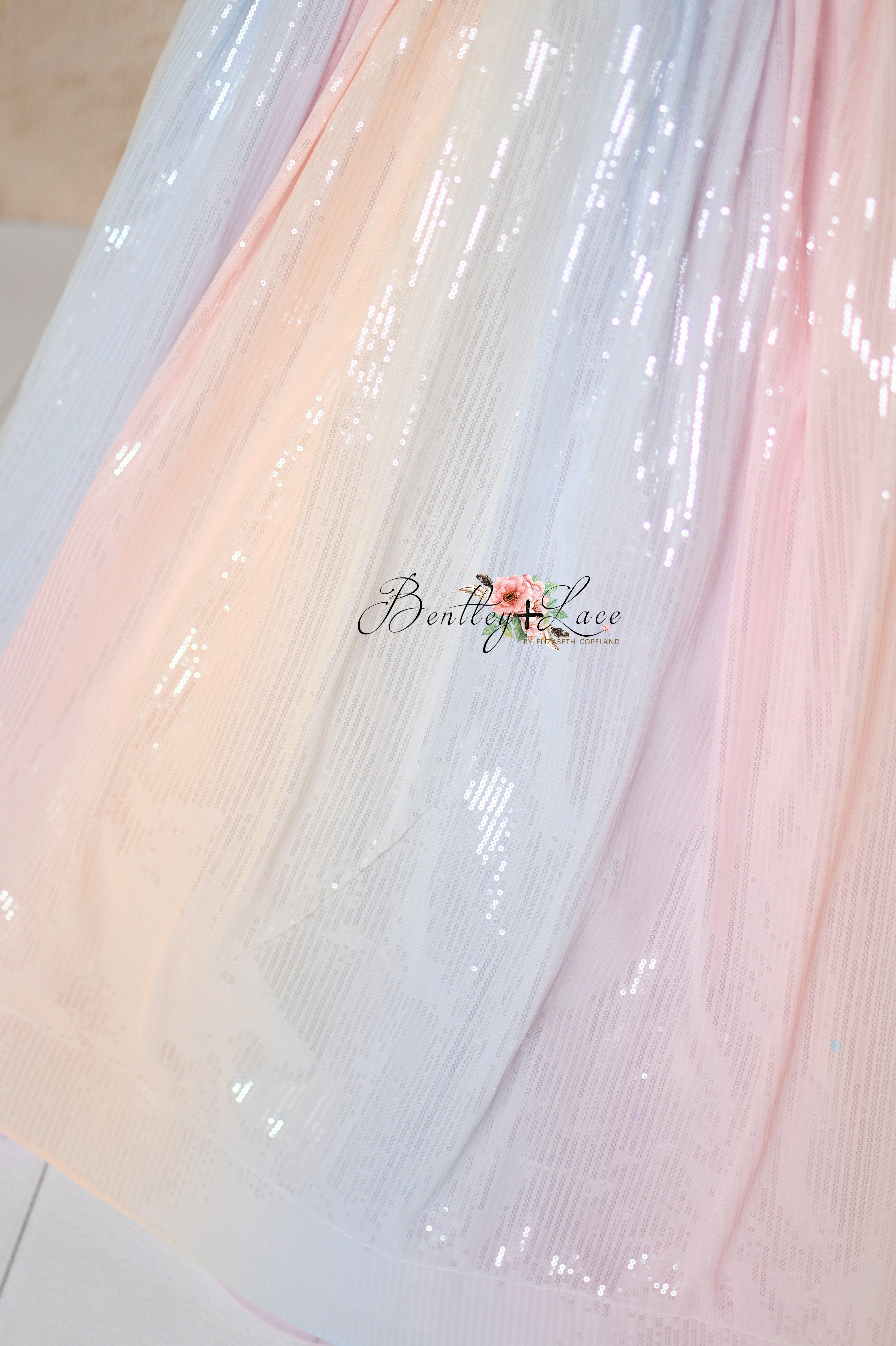 Pastel ombré fabric with delicate pleats and bow accents on the Aurora Gleam gown.