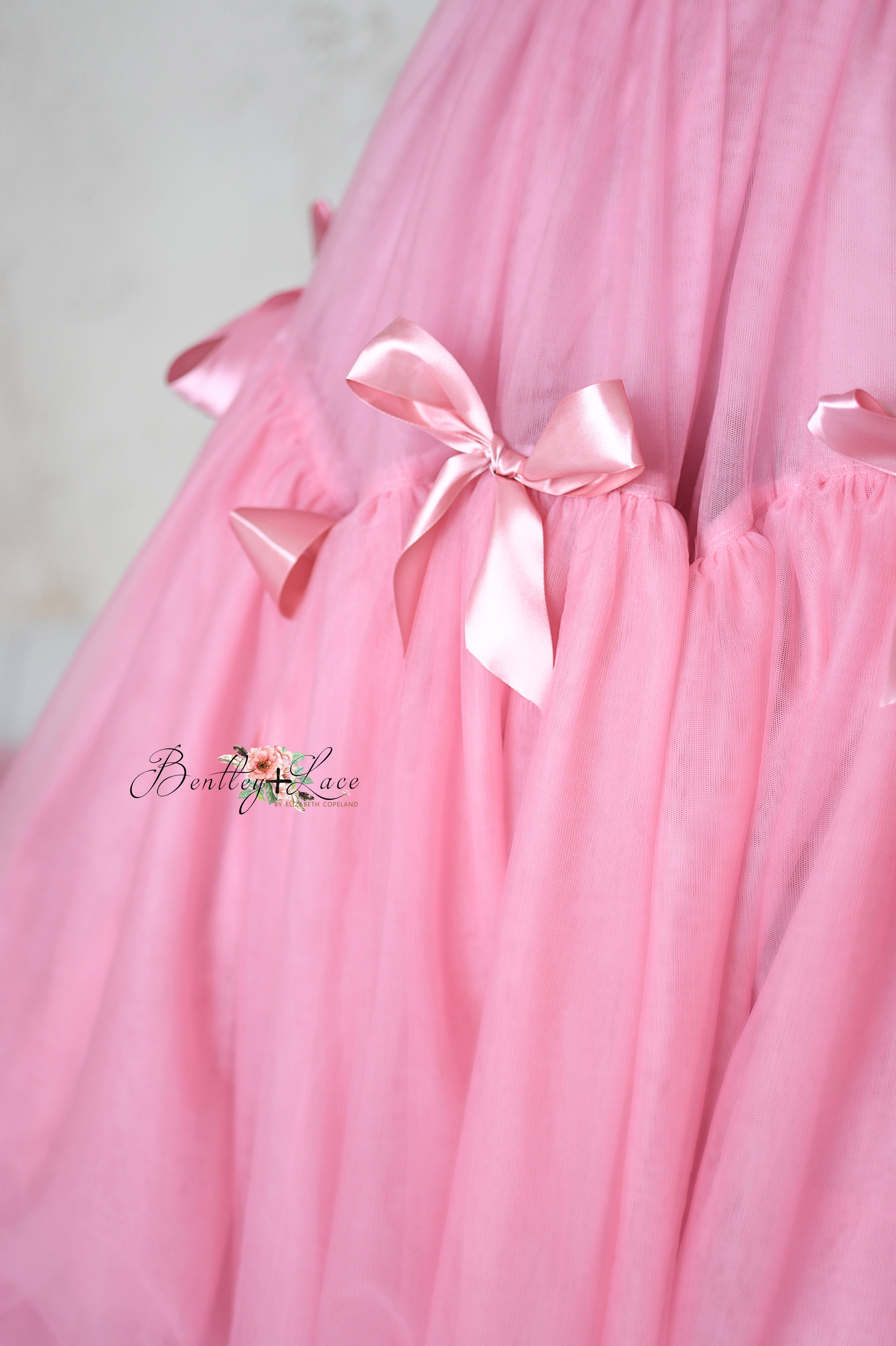 Luxurious pink formal dress with a dramatic train and layered skirt.