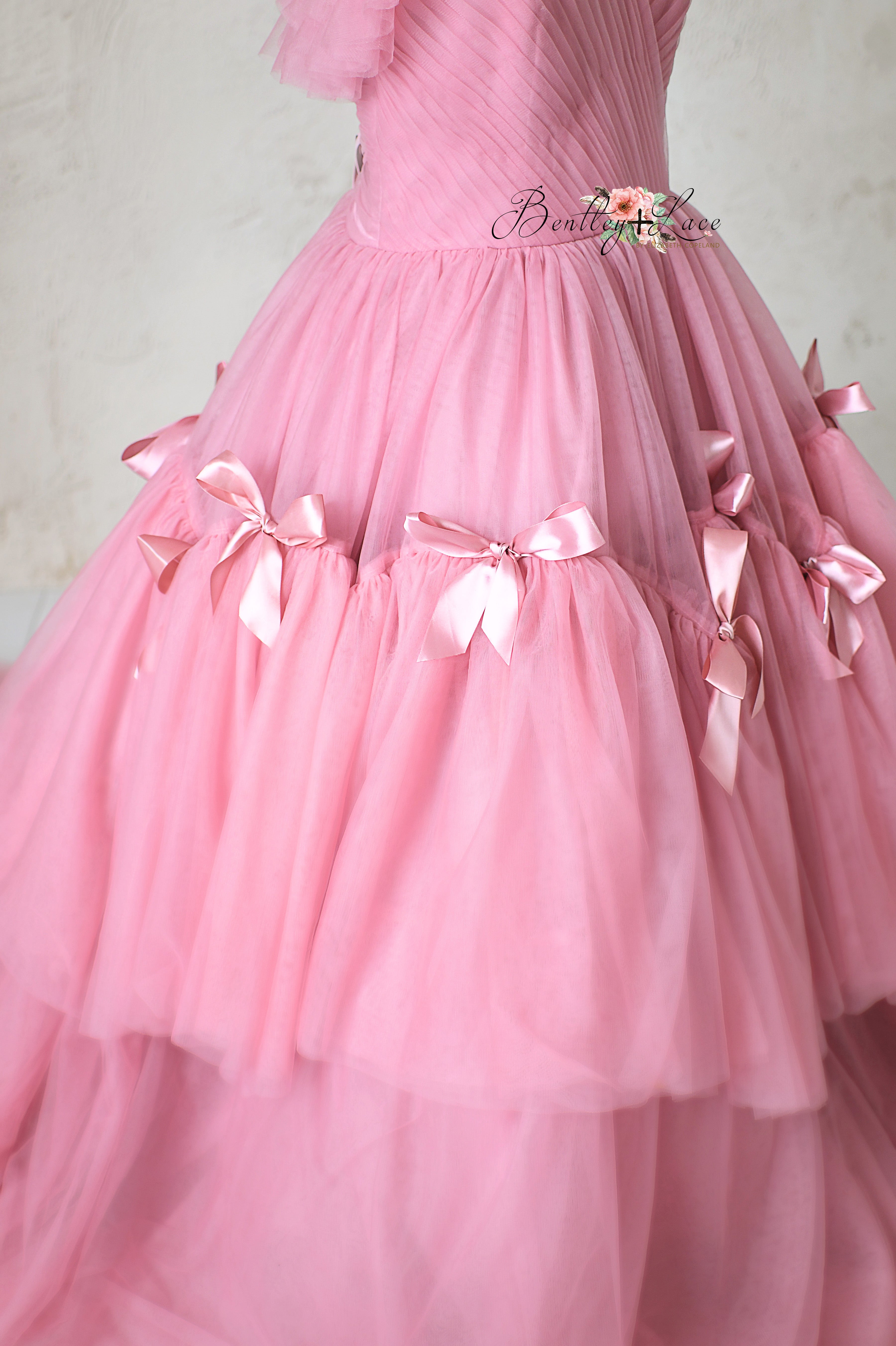 Whimsical pink princess-style gown with flowing layers and soft textures.