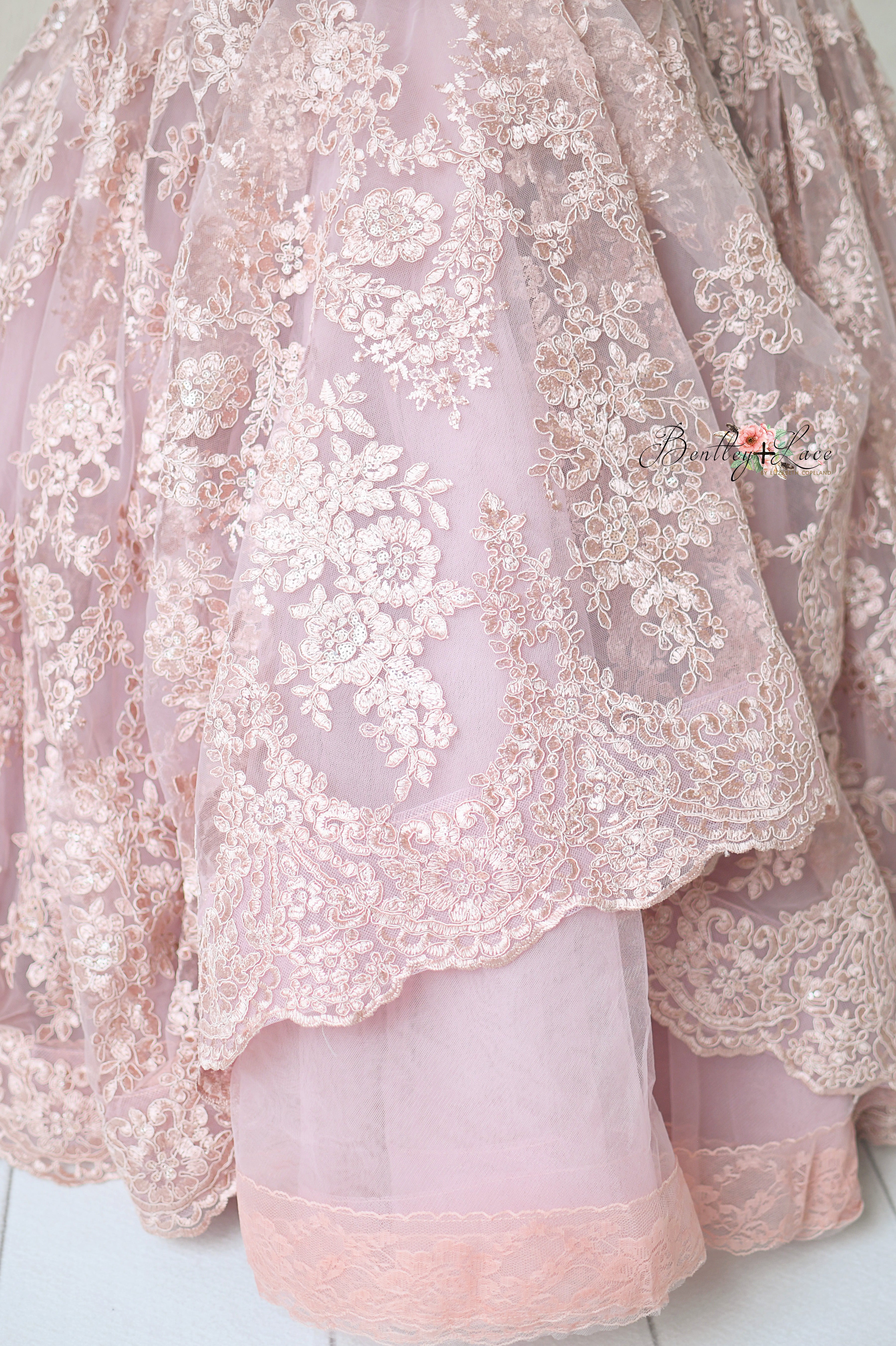 Romantic dusty mauve gown displayed on a mannequin, featuring floral lace and a soft silhouette.
