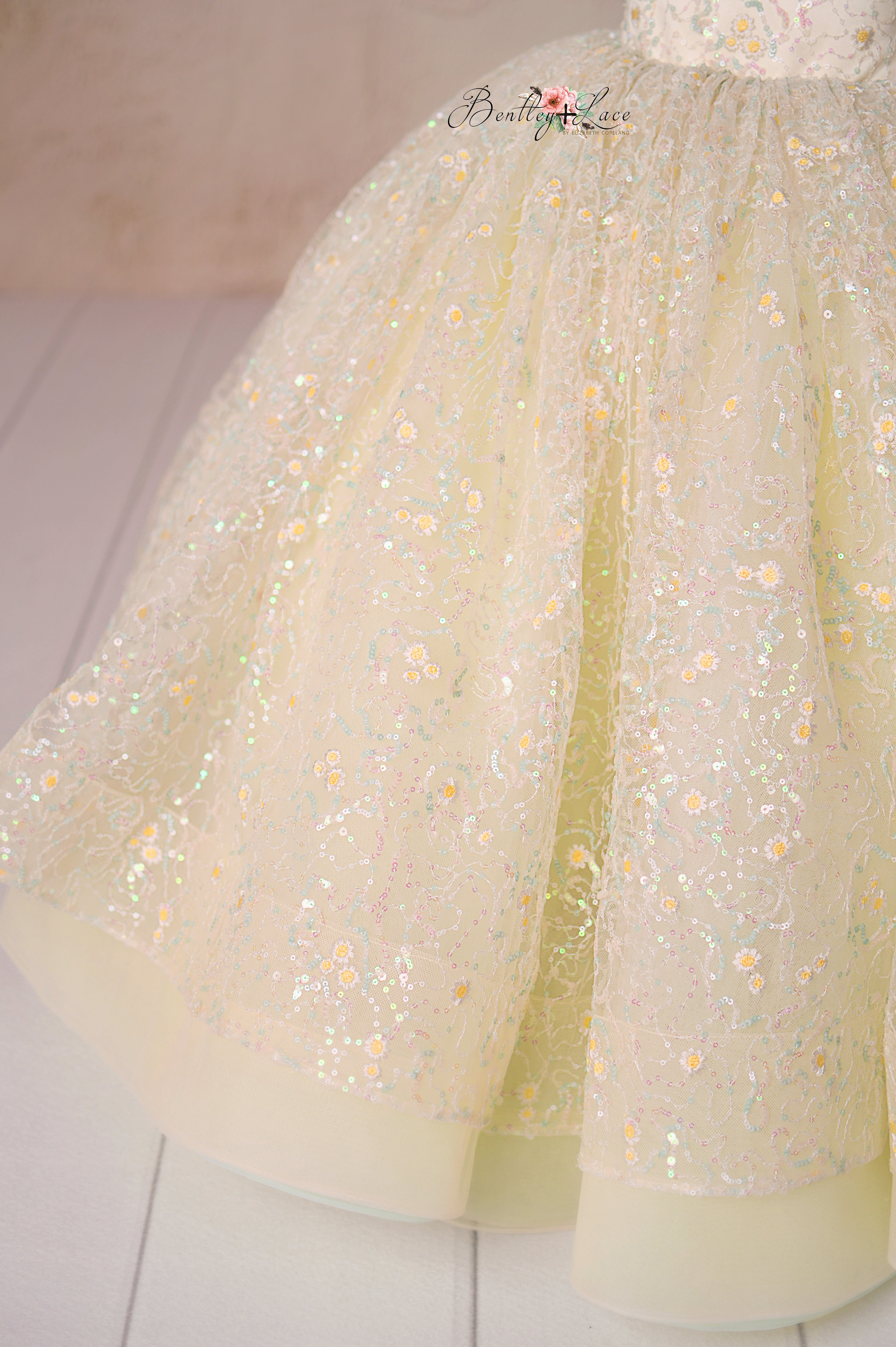 Designed for elegance, the Harmony Gown’s pleated tulle shoulders and sparkling daisy embroidery bring a touch of magic.