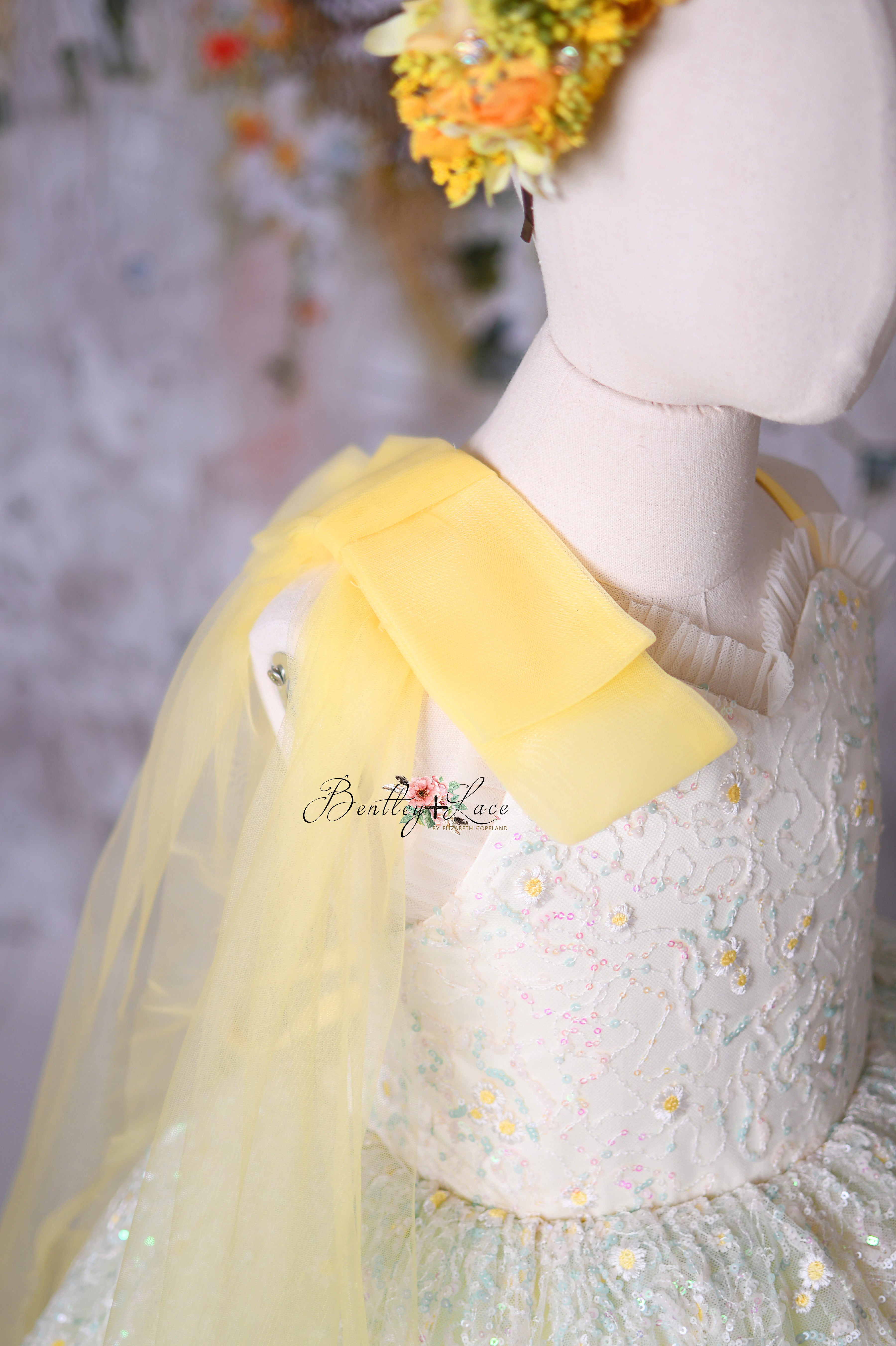 A dreamy floor-length gown with a sheer yellow shoulder sash for added elegance.