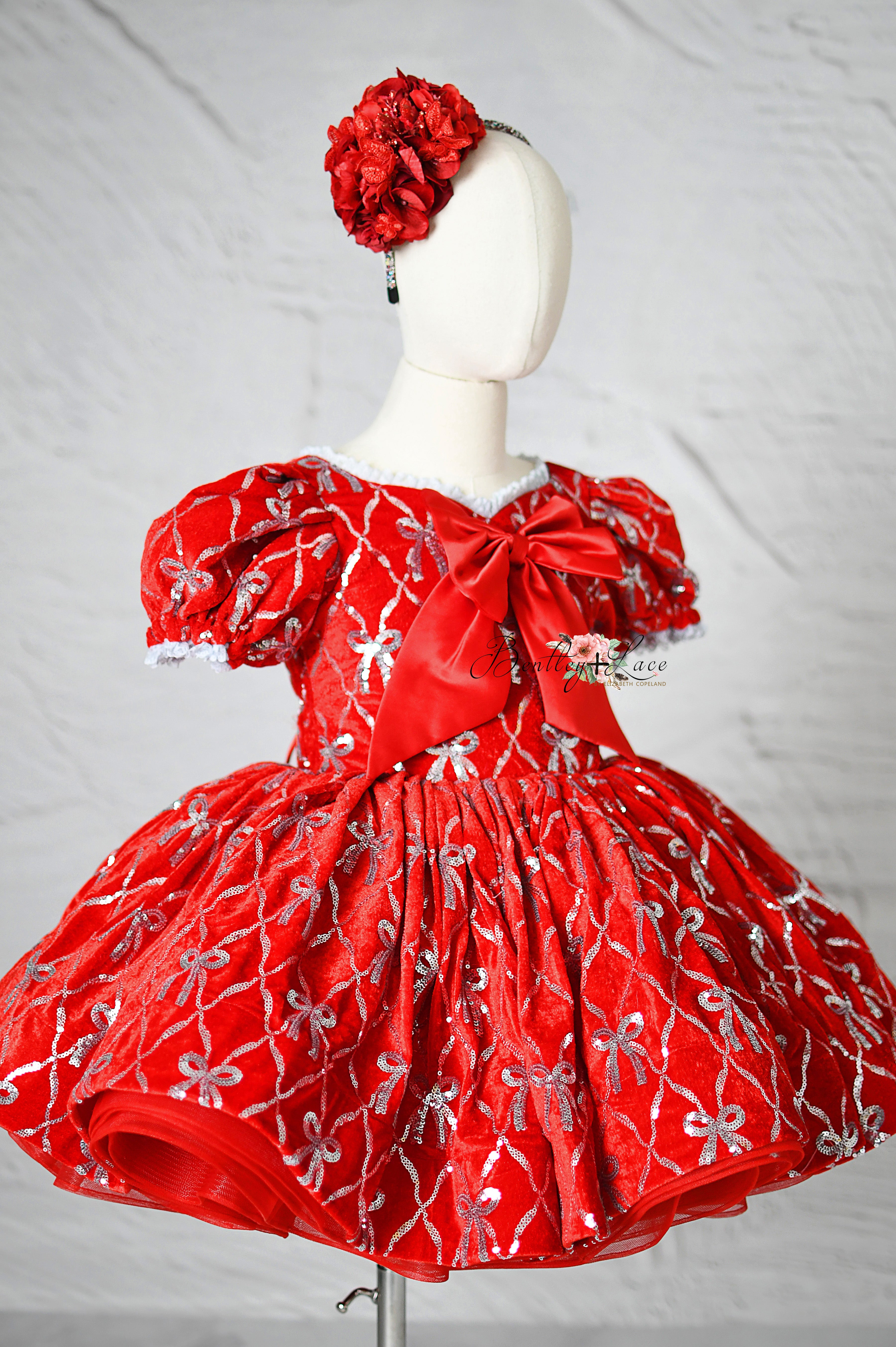 Festive red velvet girl’s gown with shimmering accents ideal for holiday events.