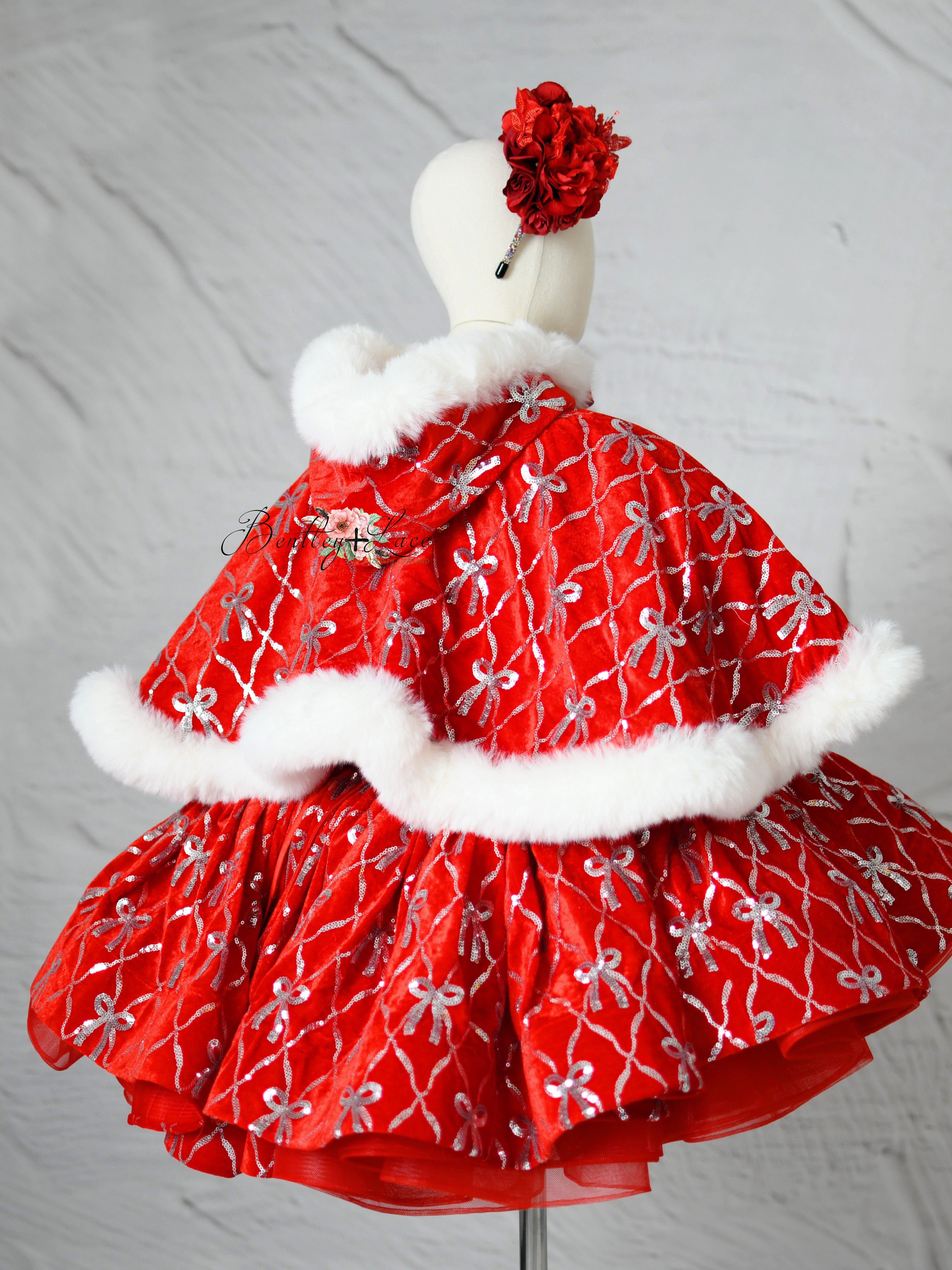 Cape draped over mannequin showcasing fur trim and festive elegance.