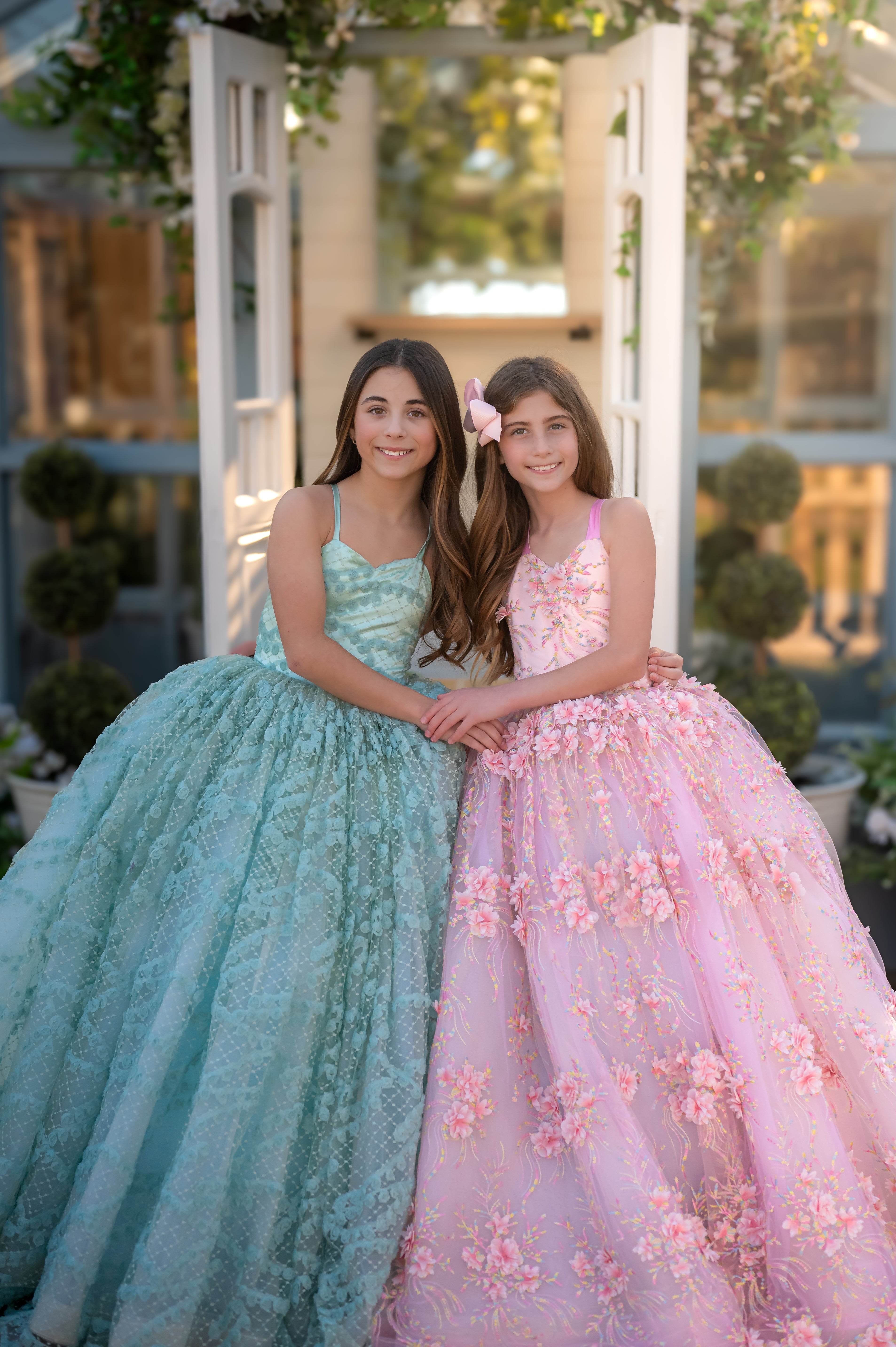 Two young women in formal dresses standing together outdoors.