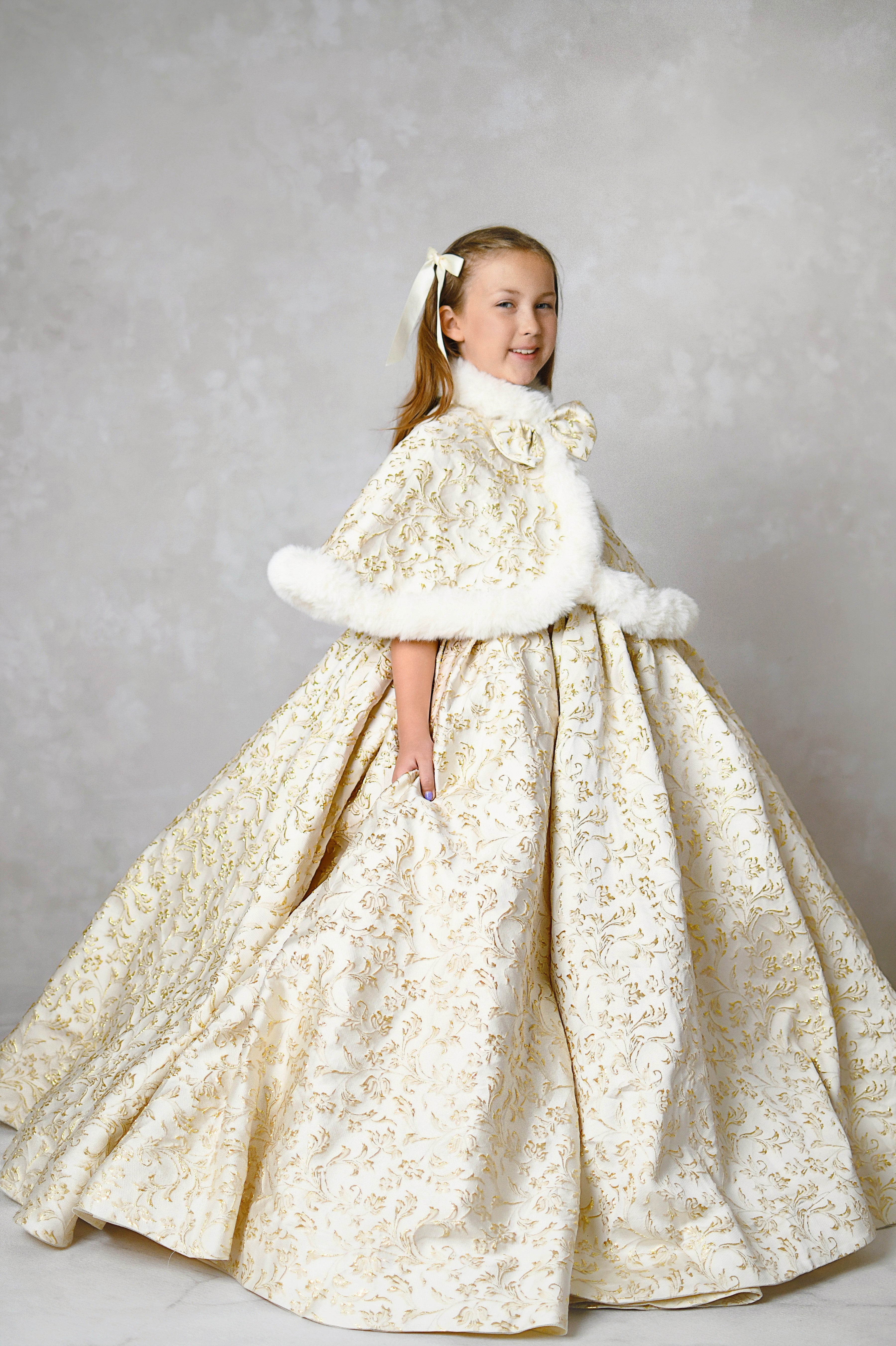 Christmas portrait of a girl in a luxurious custom gown with gold detailing and a floral headpiece.
