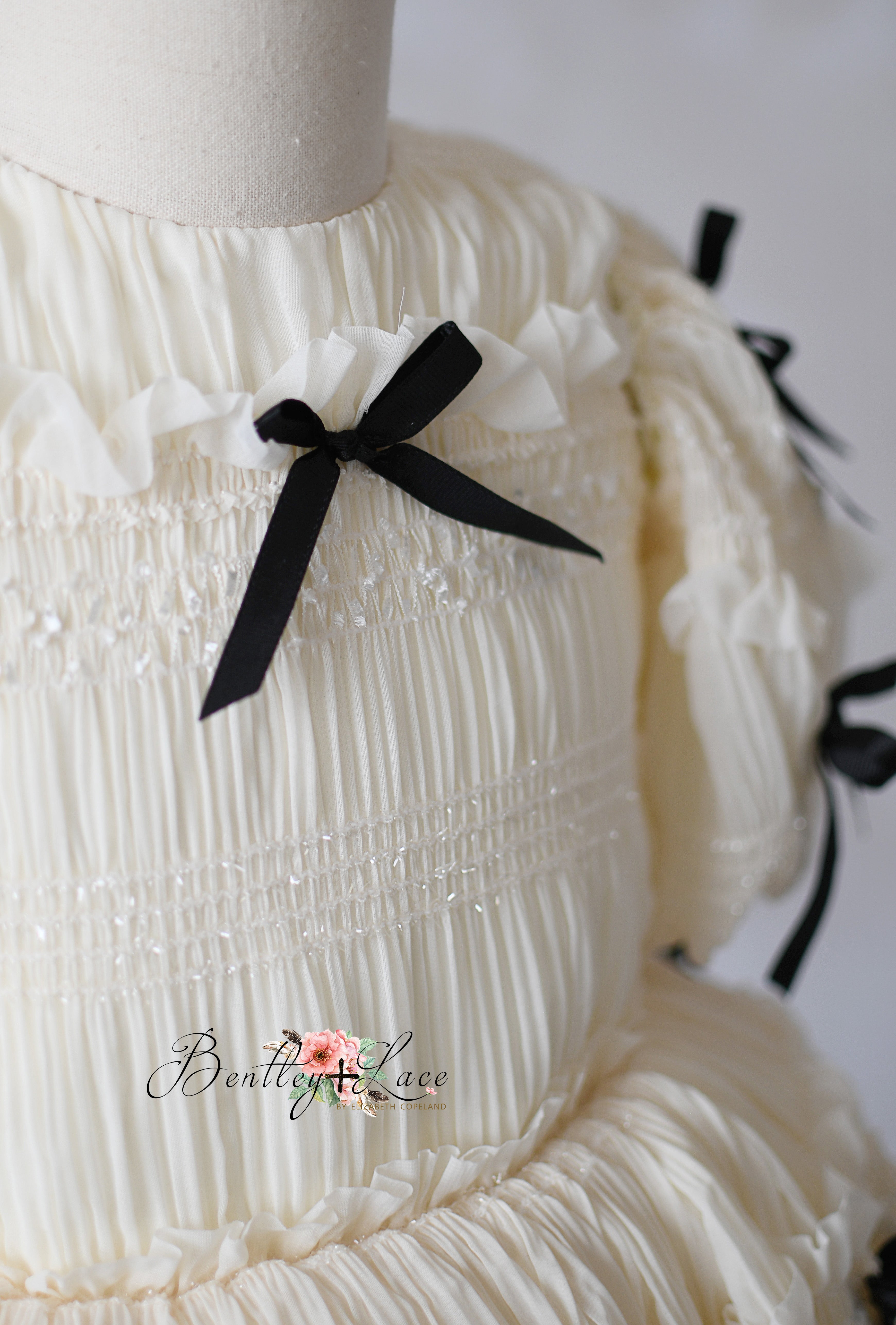 Frosted Ribboncake dress by Bentley and Lace, featuring soft tulle, smocking, and elegant black bow details.