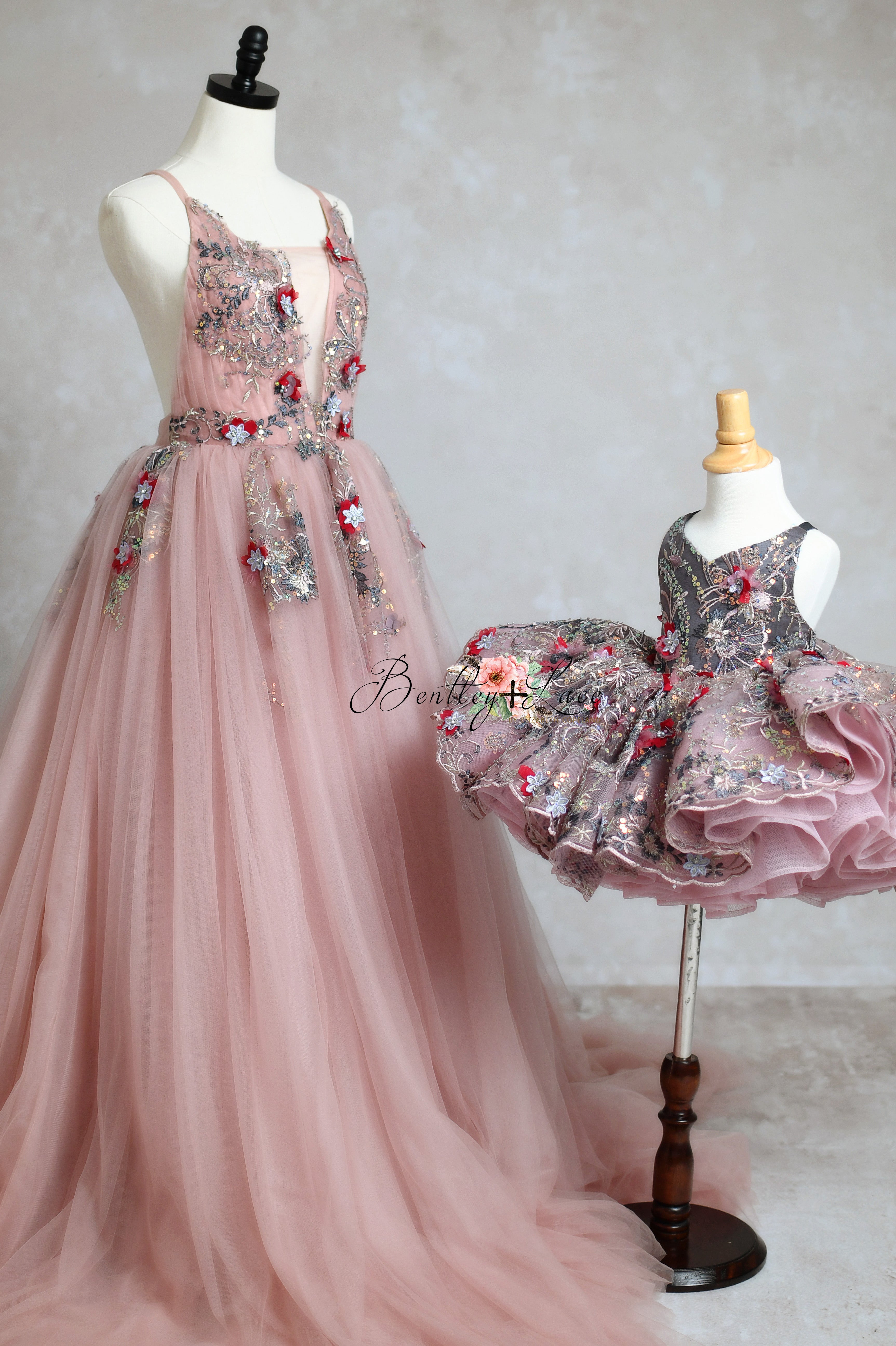 The Dillon gown, made from beaded sequin floral fabric and soft tulle, showcases a deep V-cut bodice with hand-sewn floral appliques, an open back with adjustable shoulder ties, and a flowing tulle skirt.