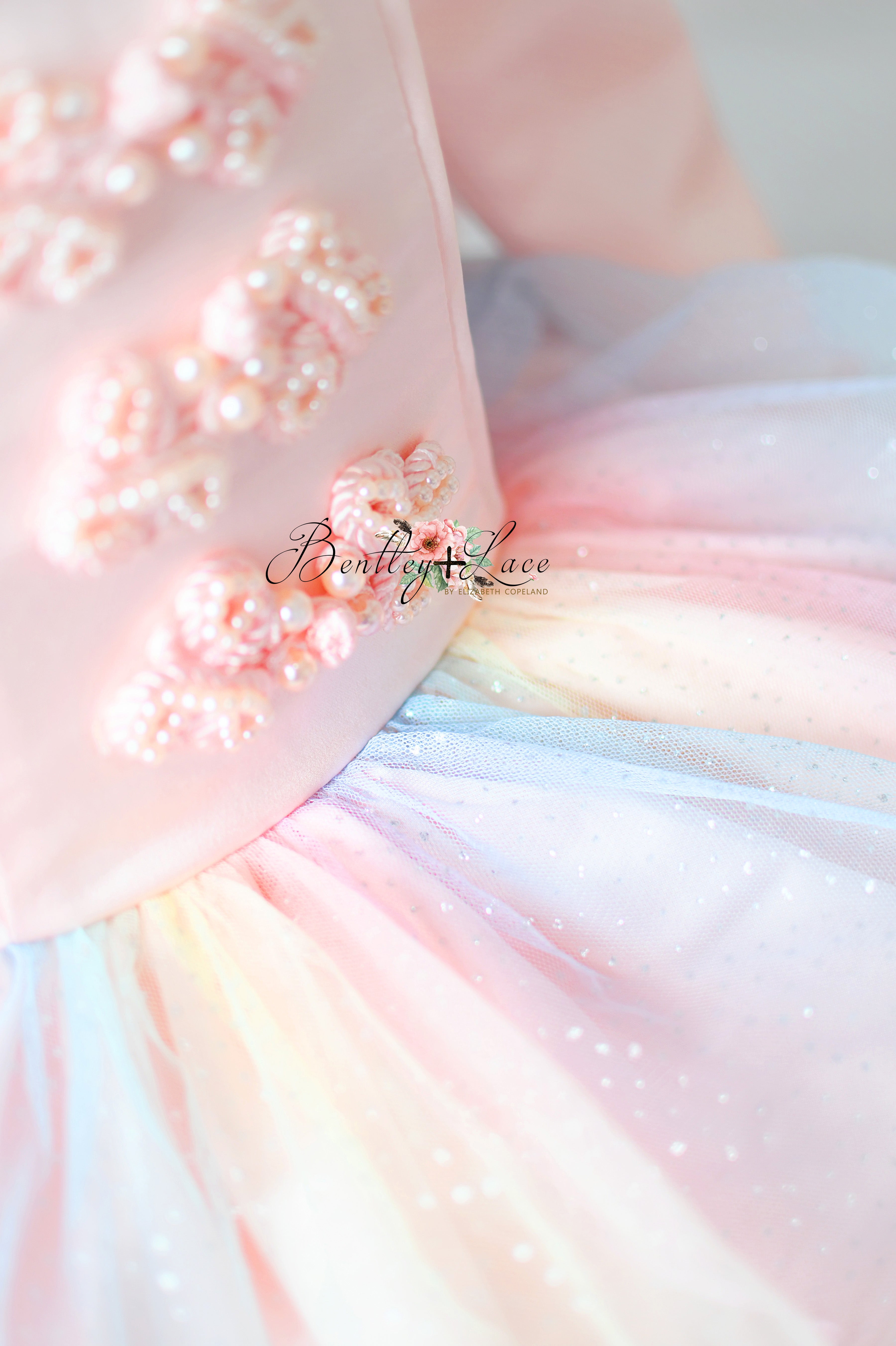 Close-up of a pastel-colored dress with floral embellishments and 'Boutique Lace' branding.
