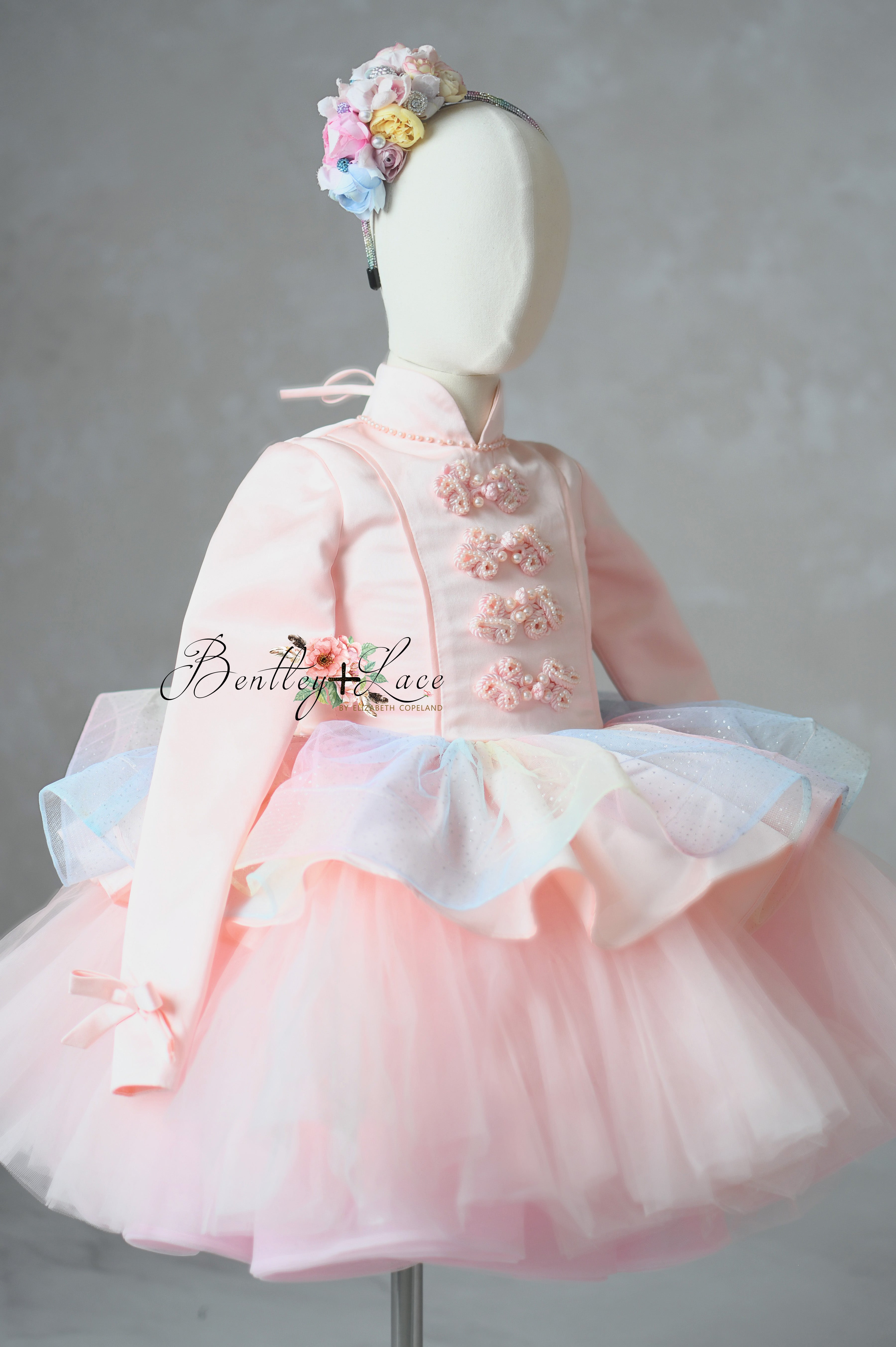 Pink traditional dress with floral headband on a mannequin against a gray background