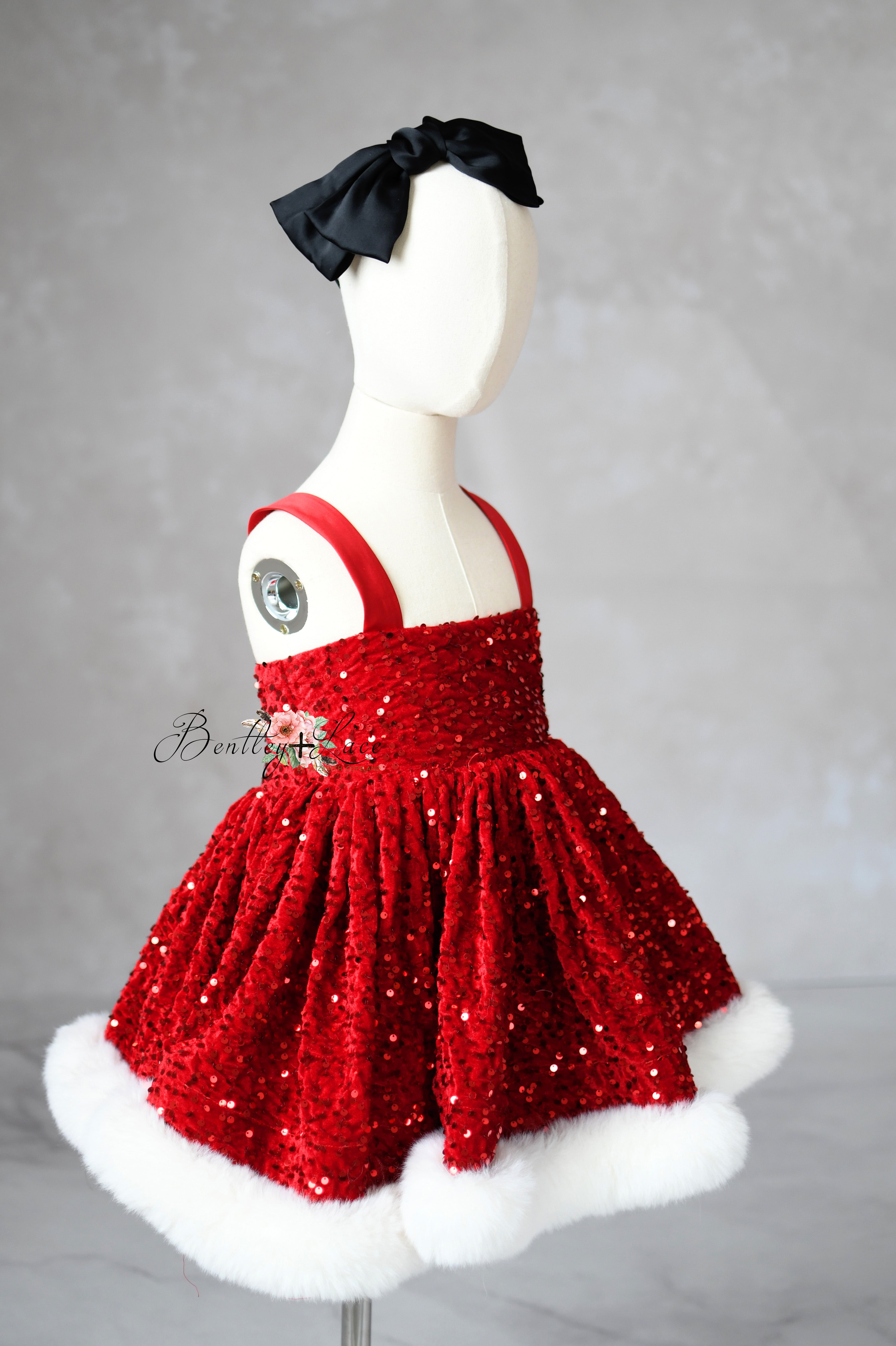 Red sequined dress with white fur trim on a mannequin against a gray background