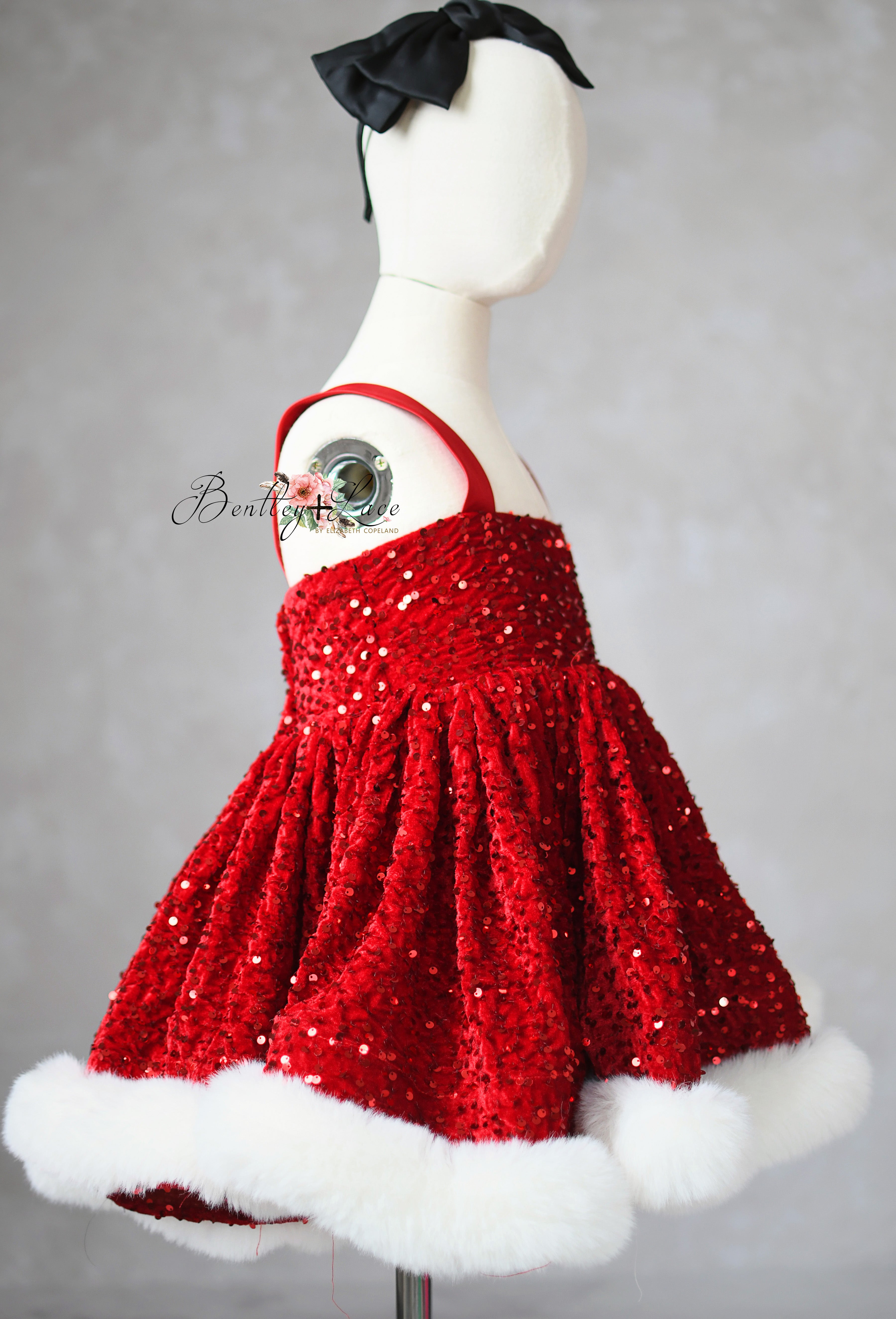 Red sequin dress with white fur trim on a mannequin against a gray background