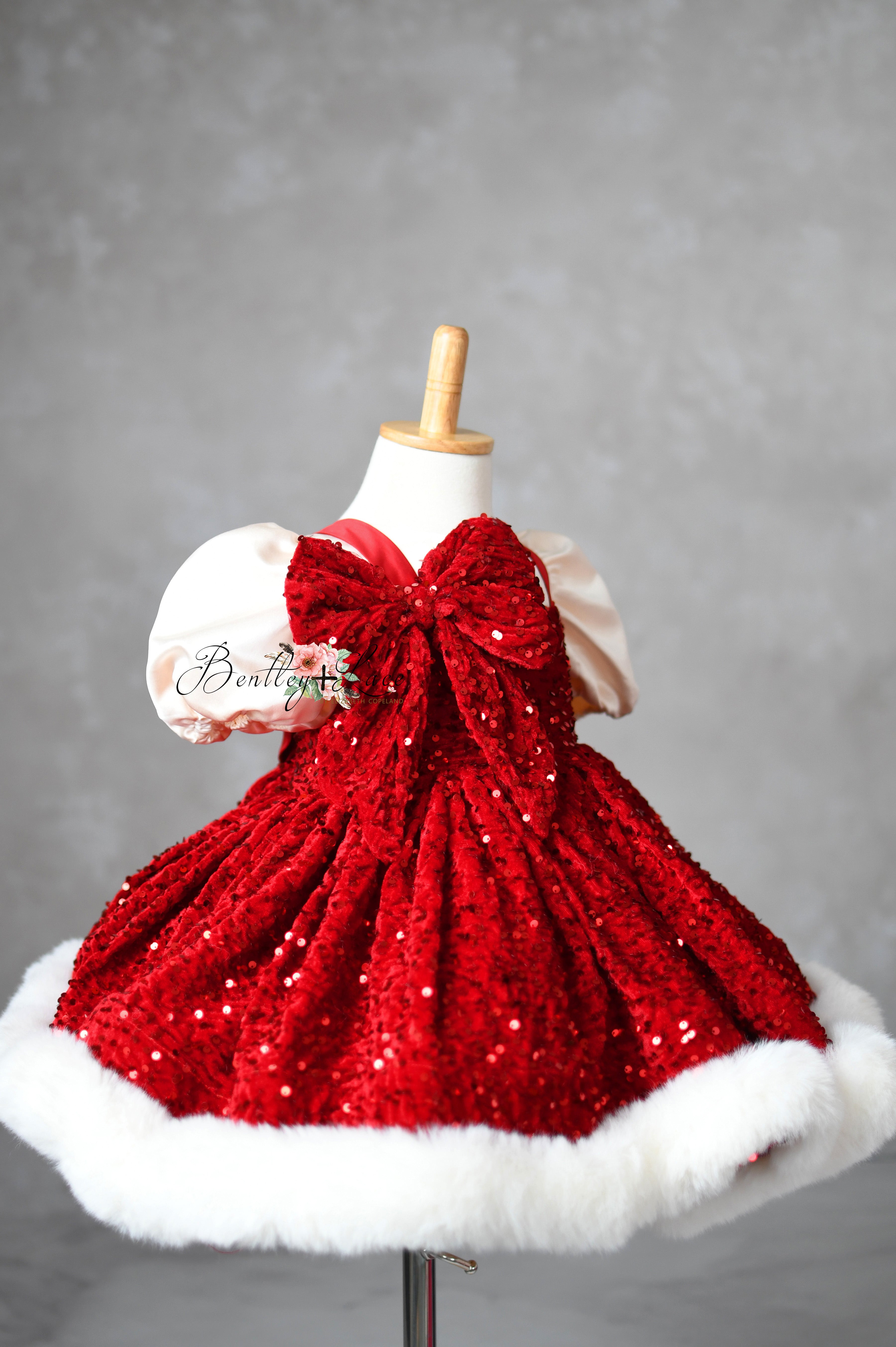 Holiday dress featuring detachable oversized bow and fur hem.